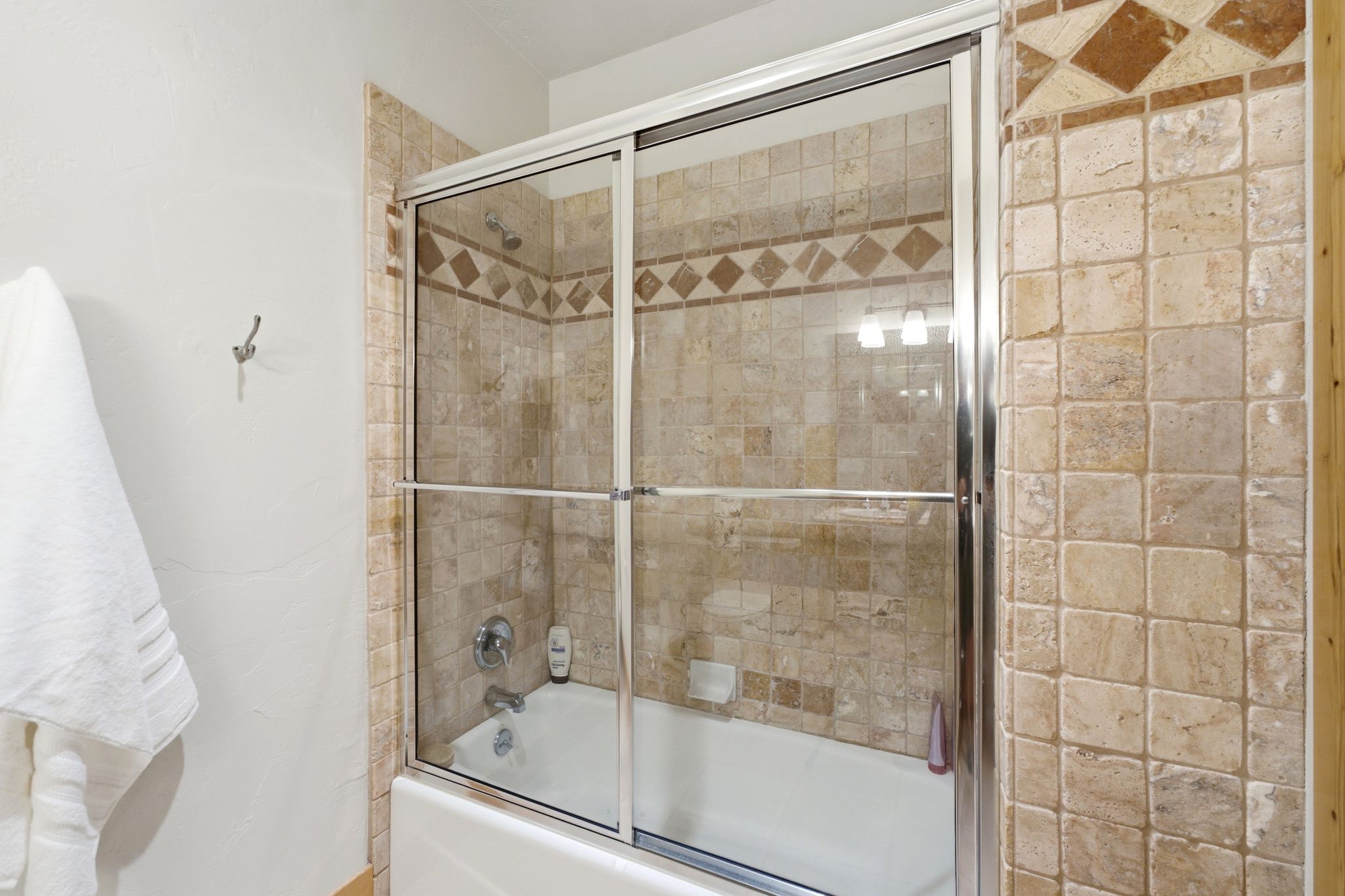 Bathtub and shower combination featuring a glass enclosure with chrome framing, integrated showerhead, and tile surround