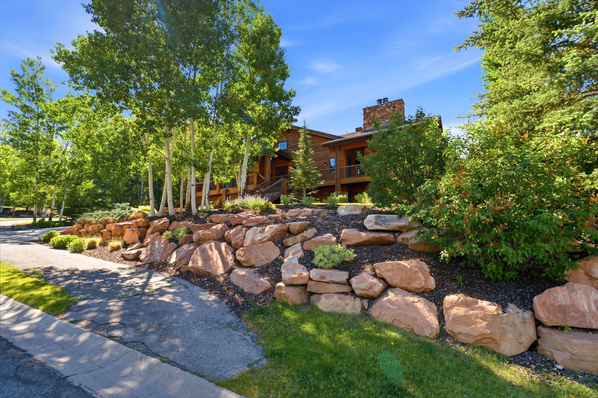 Wood-sided residence featuring a stone chimney and an upper-level balcony