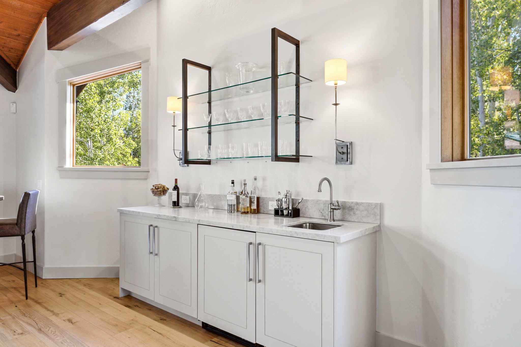 Wet bar featuring white cabinetry, a light-toned countertop, and an undermount sink with a gooseneck faucet