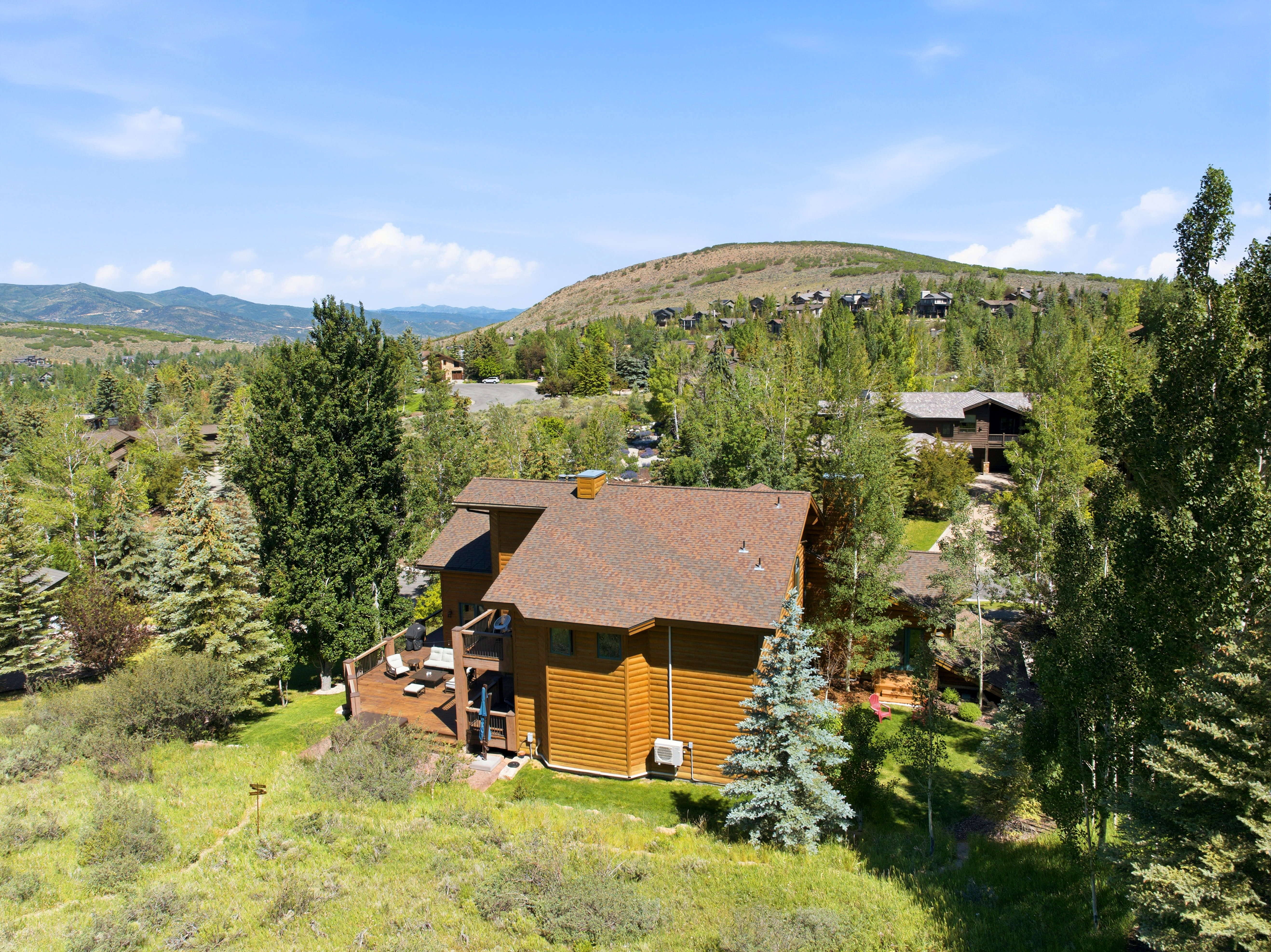 Cedar-sided residence featuring a multi-level deck, a shingle roof, and surrounding mature trees