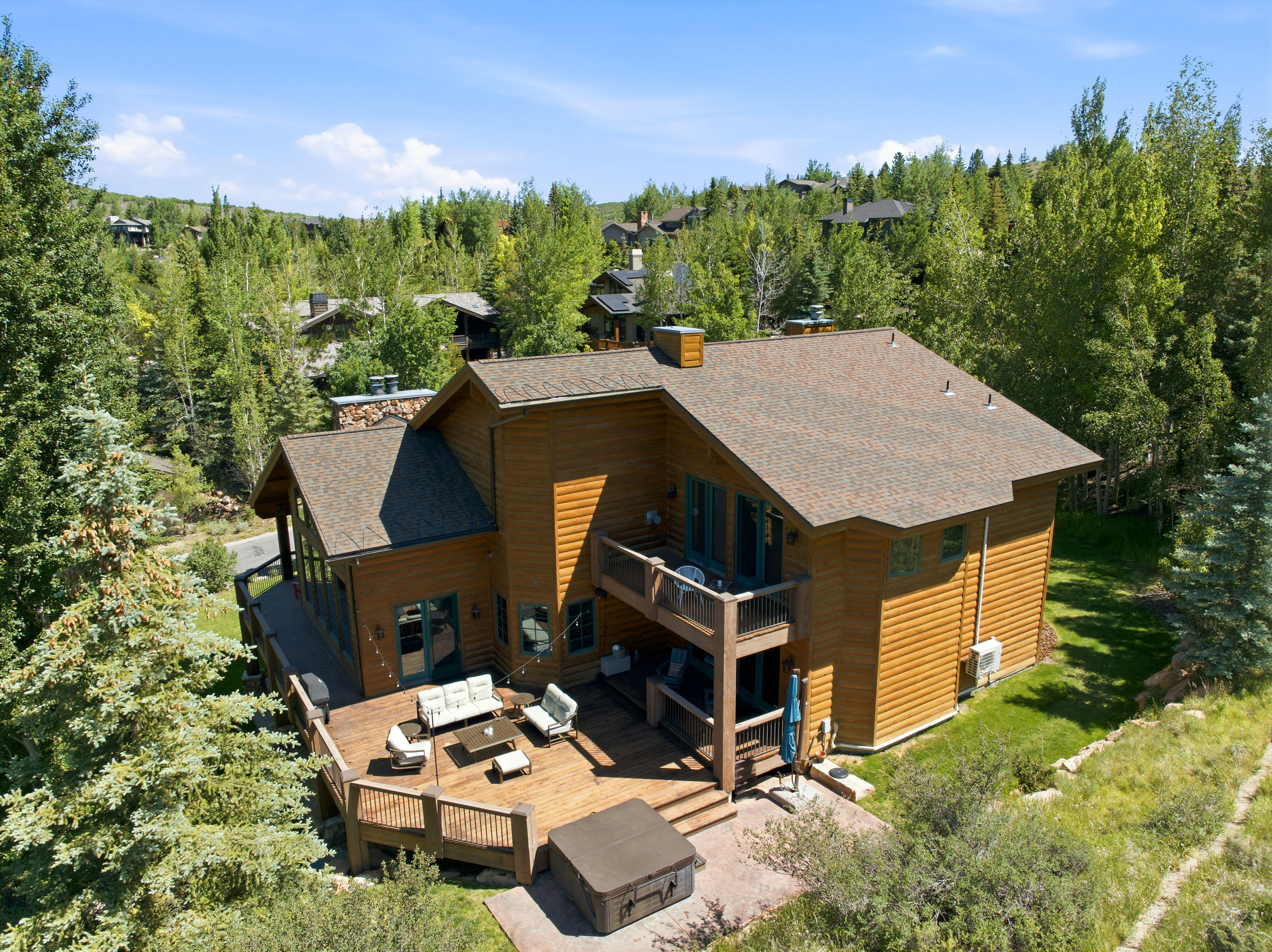 Multi-level wood-sided residence featuring a spacious outdoor deck, integrated hot tub, and a second-story balcony