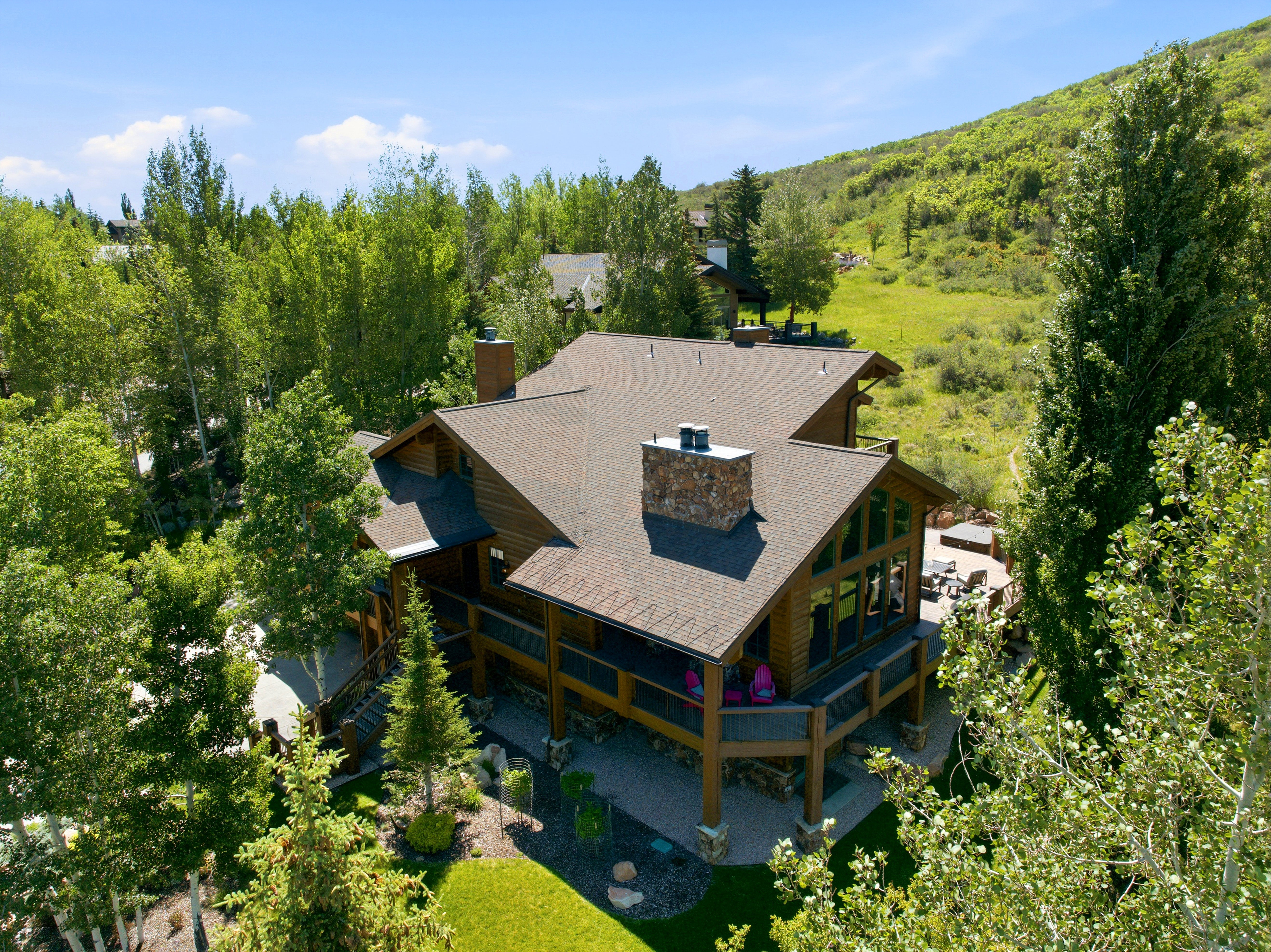 Wood-sided residence featuring a multi-level deck, stone chimney, and gable roof