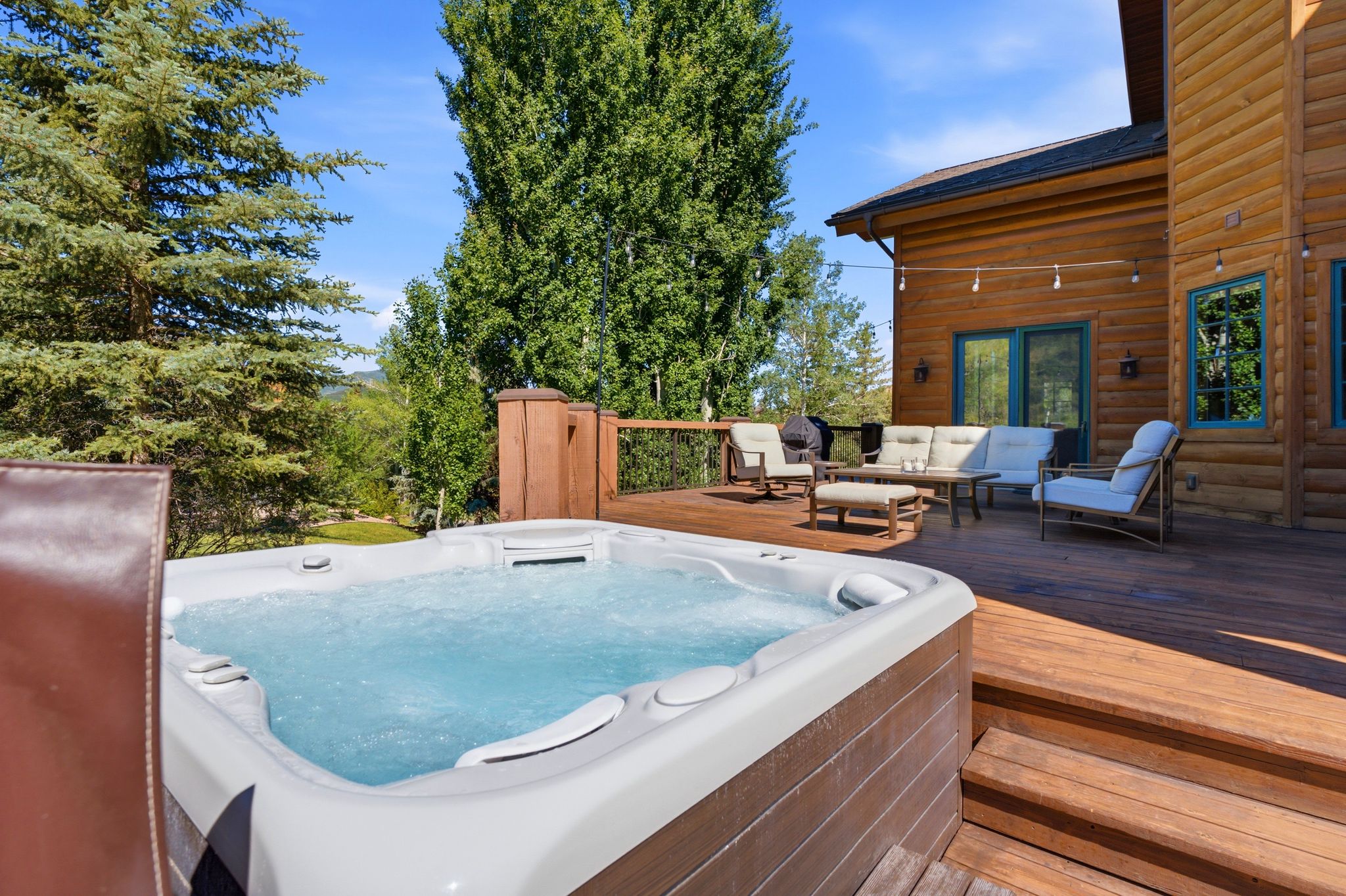 Outdoor deck featuring a built-in hot tub, log cabin style siding, a wooden railing, and extensive decking