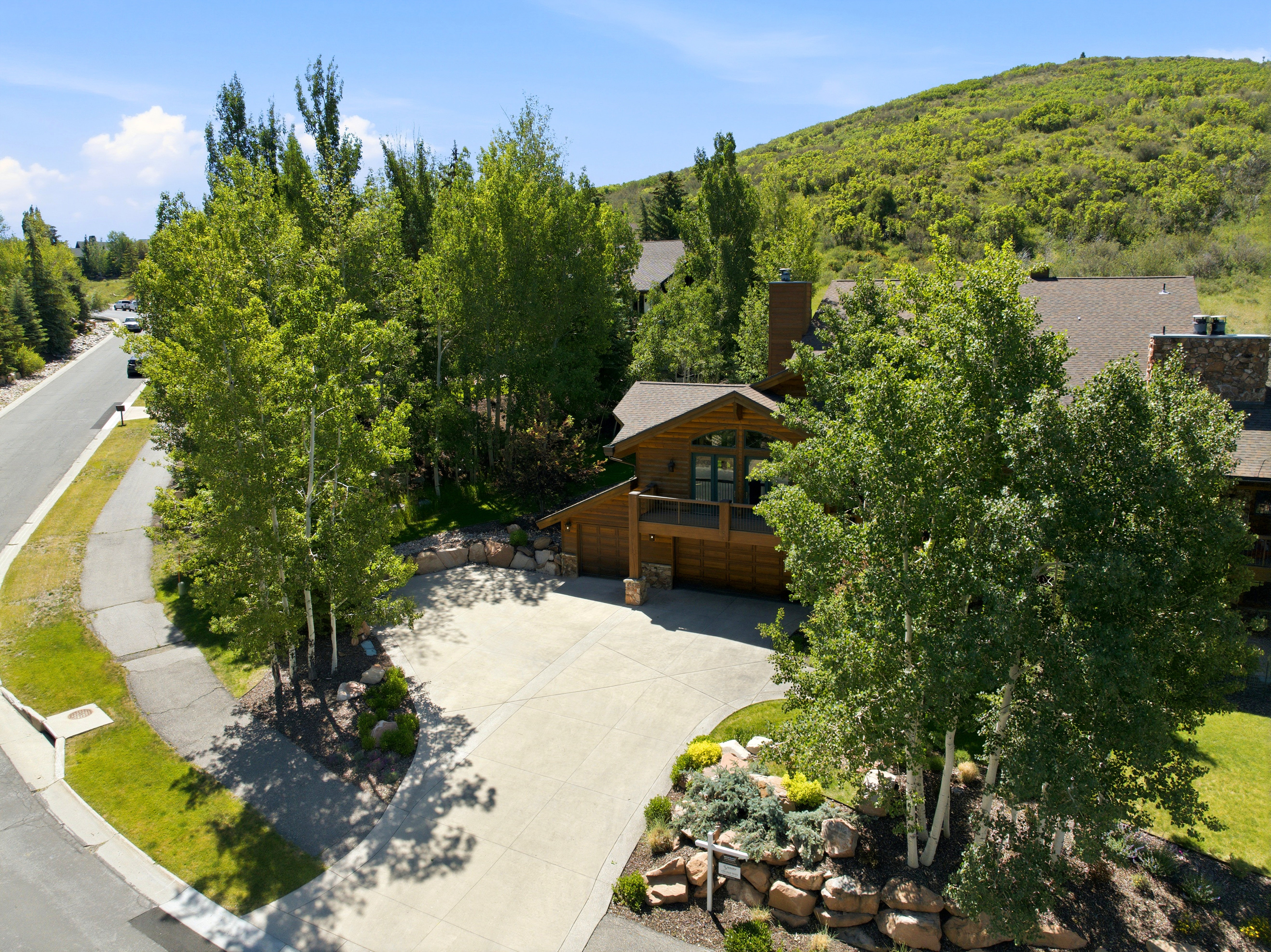 Wood-sided residence with a covered balcony, integrated garage, and stone chimney accents