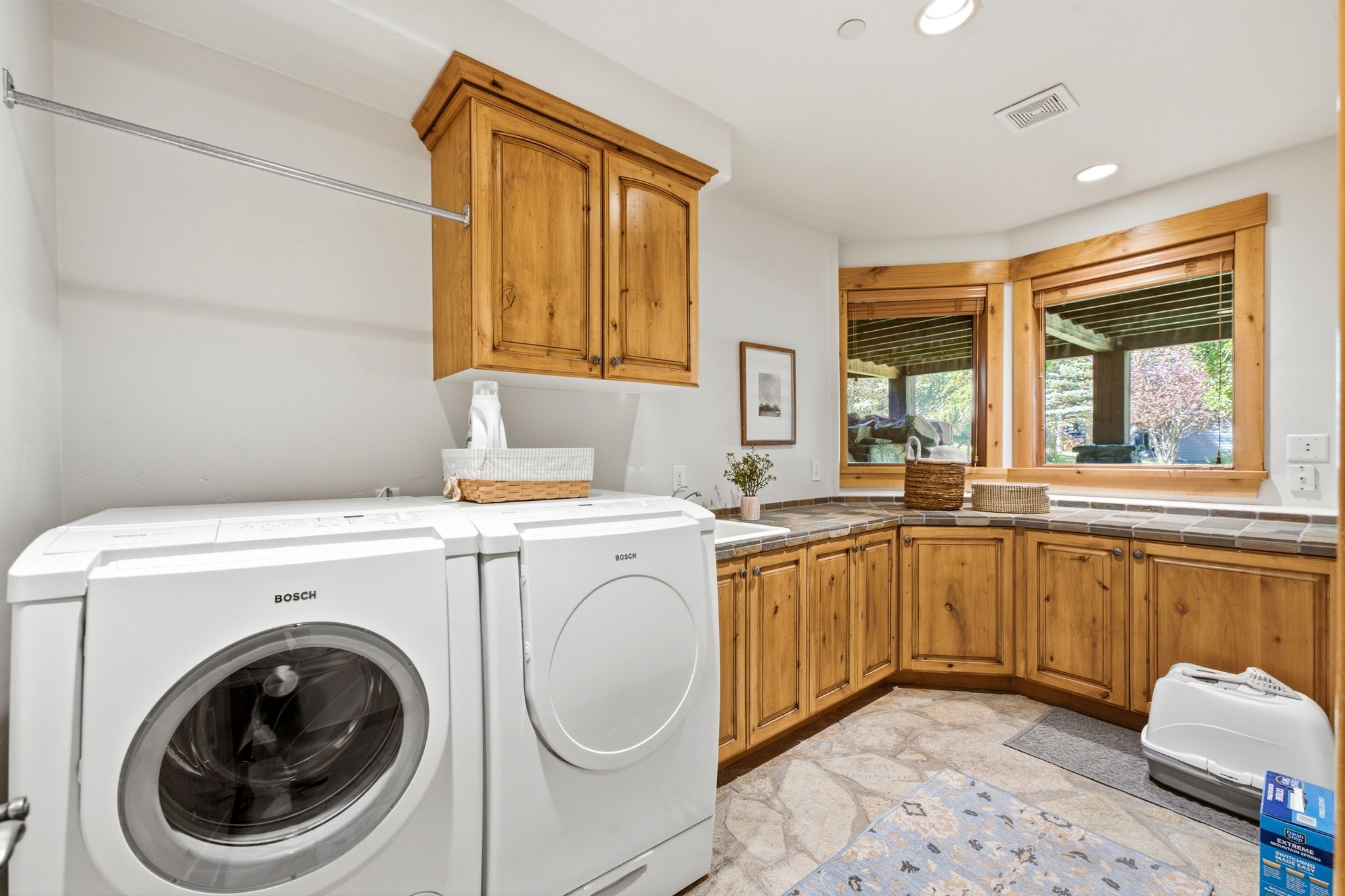Laundry room featuring light wood cabinetry, stone-finish countertops, and an integrated drying rod