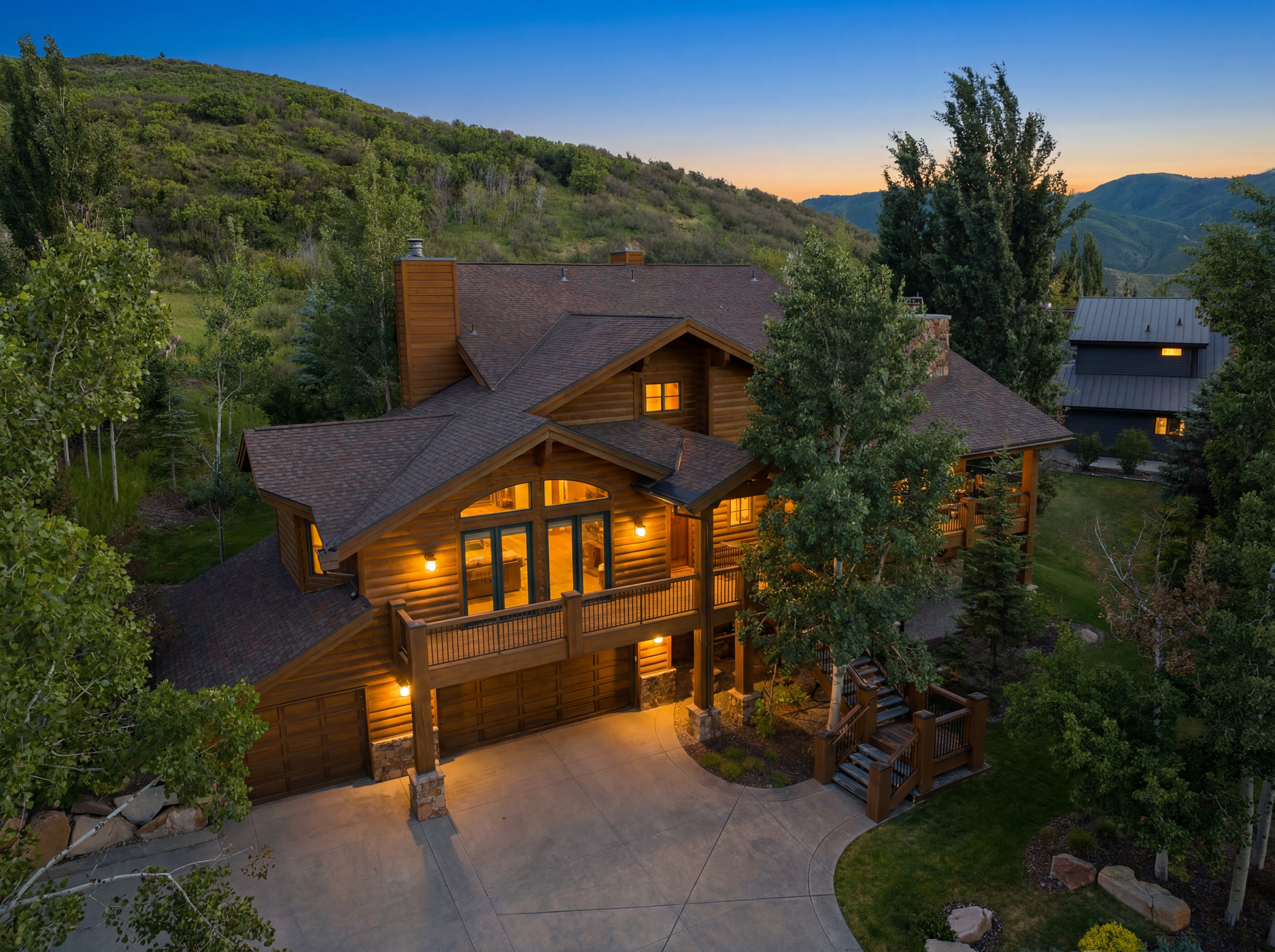 Rustic log-cabin style home featuring a multi-level design, attached garage, and a prominent balcony with a wooden railing