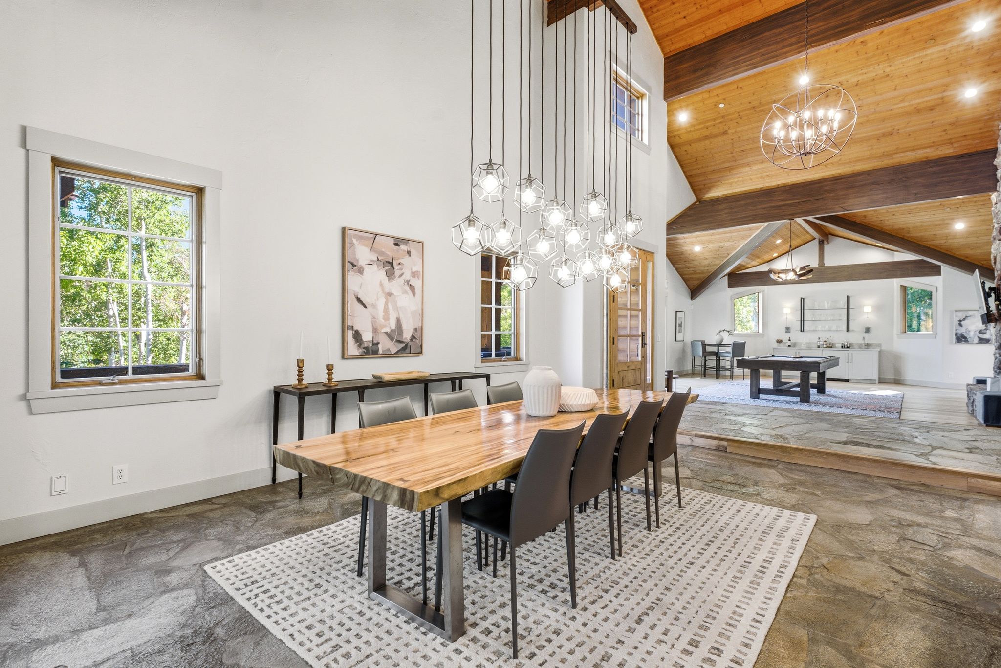 Spacious interior featuring natural stone flooring, high vaulted ceilings with wood paneling and exposed beams, and a multi-level layout