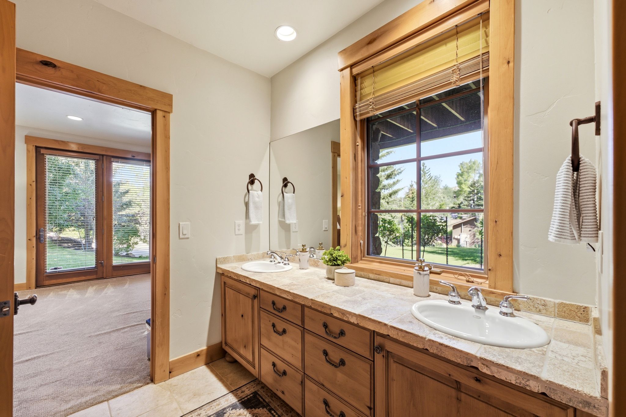 Double vanity with wood cabinetry, stone countertop, two undermount sinks, and bronze hardware