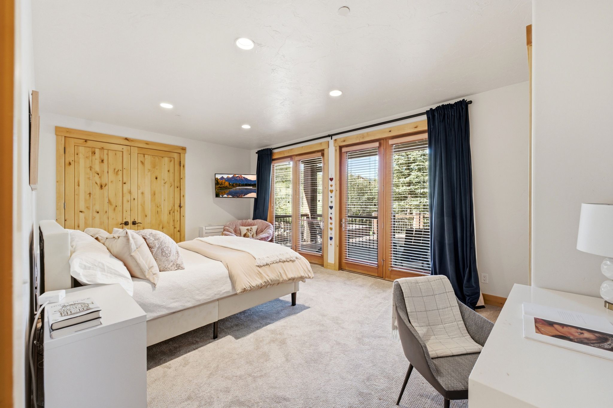 Bright bedroom featuring double French doors leading to an outdoor balcony, recessed lighting, light wood-finish bi-fold closet doors, and carpeted flooring
