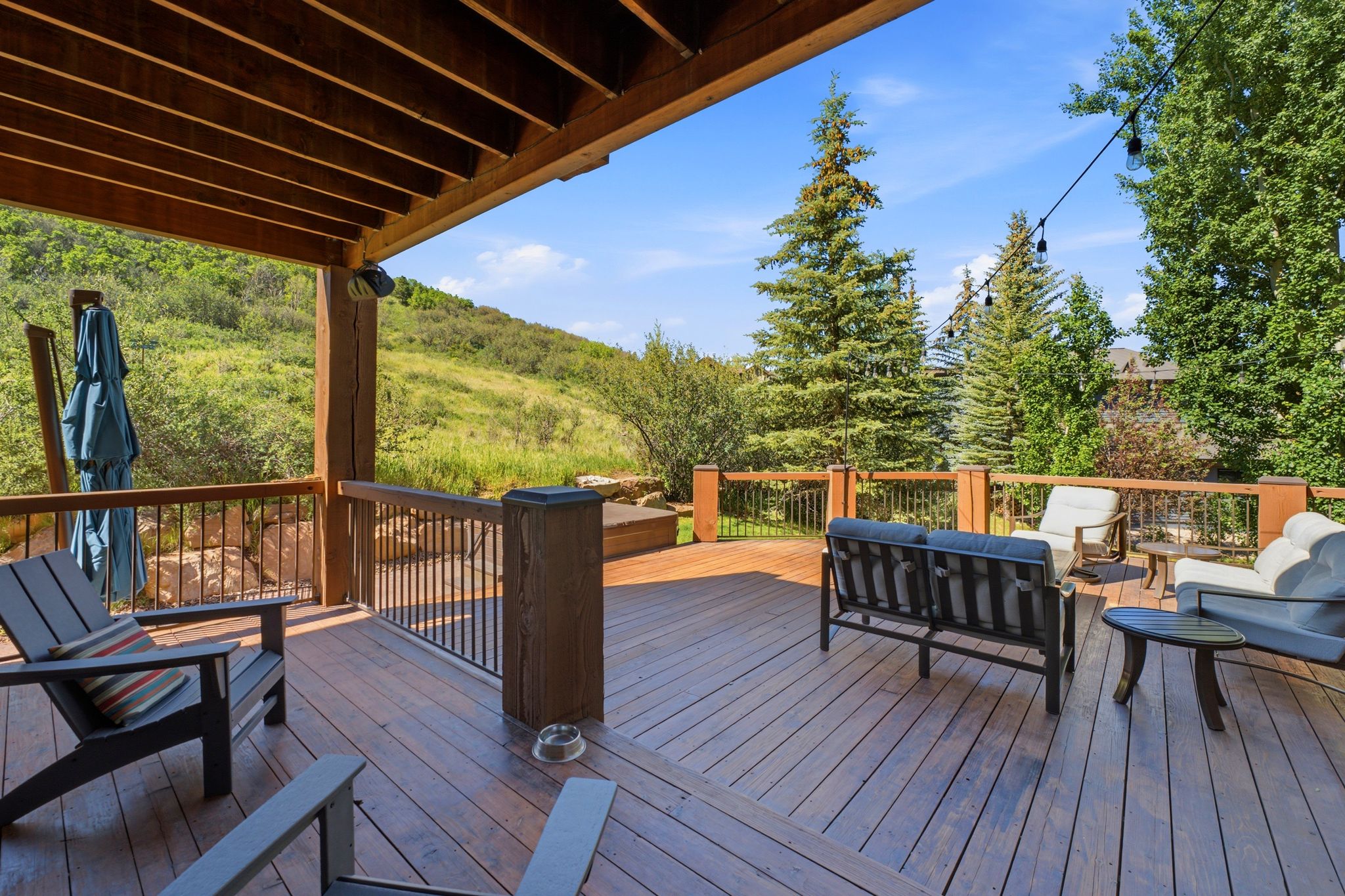 Spacious outdoor deck featuring wood-finish flooring, sturdy wood pillars, and black metal railings