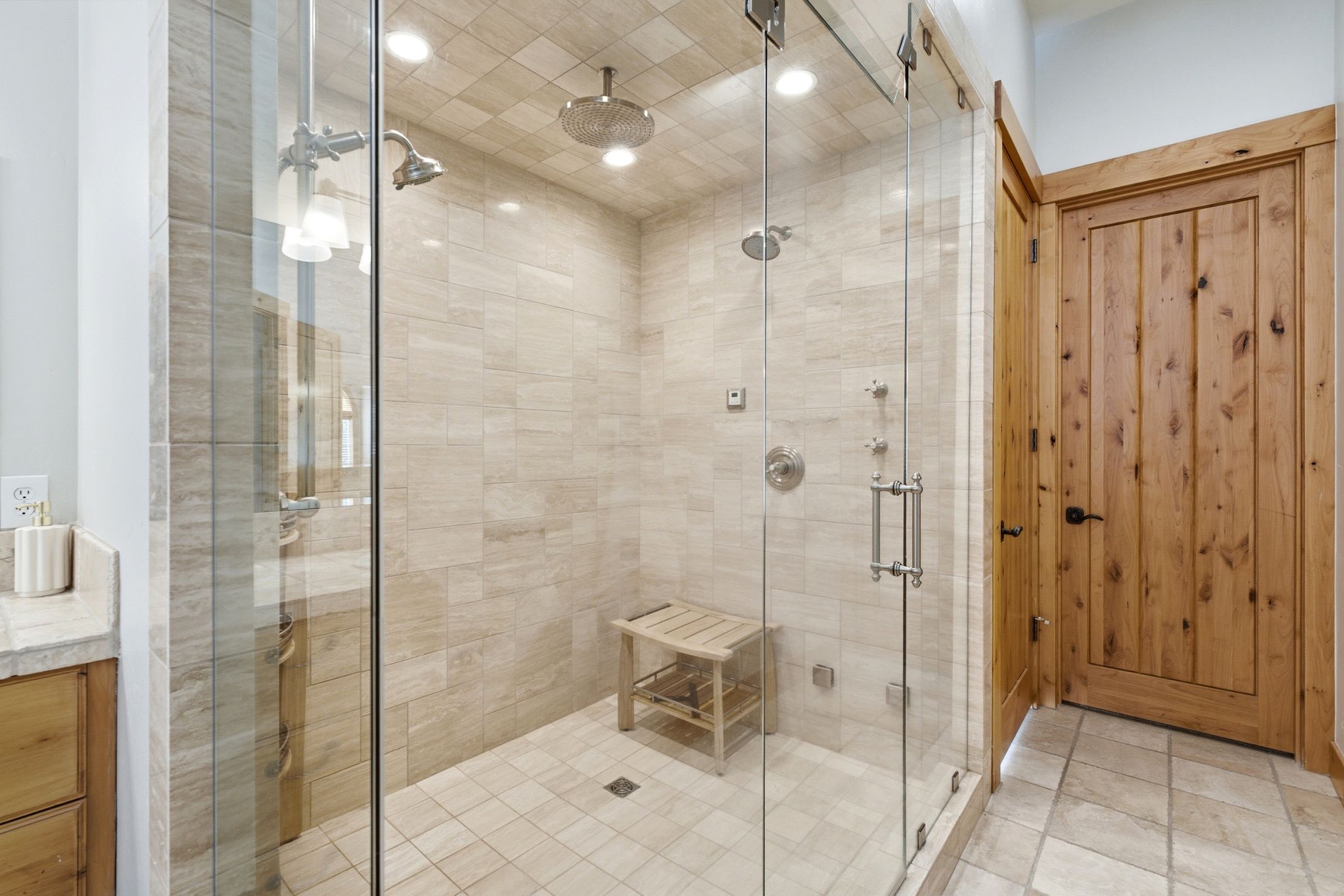 Glass-enclosed shower featuring a rainfall showerhead, handheld shower fixture, and tiled walls