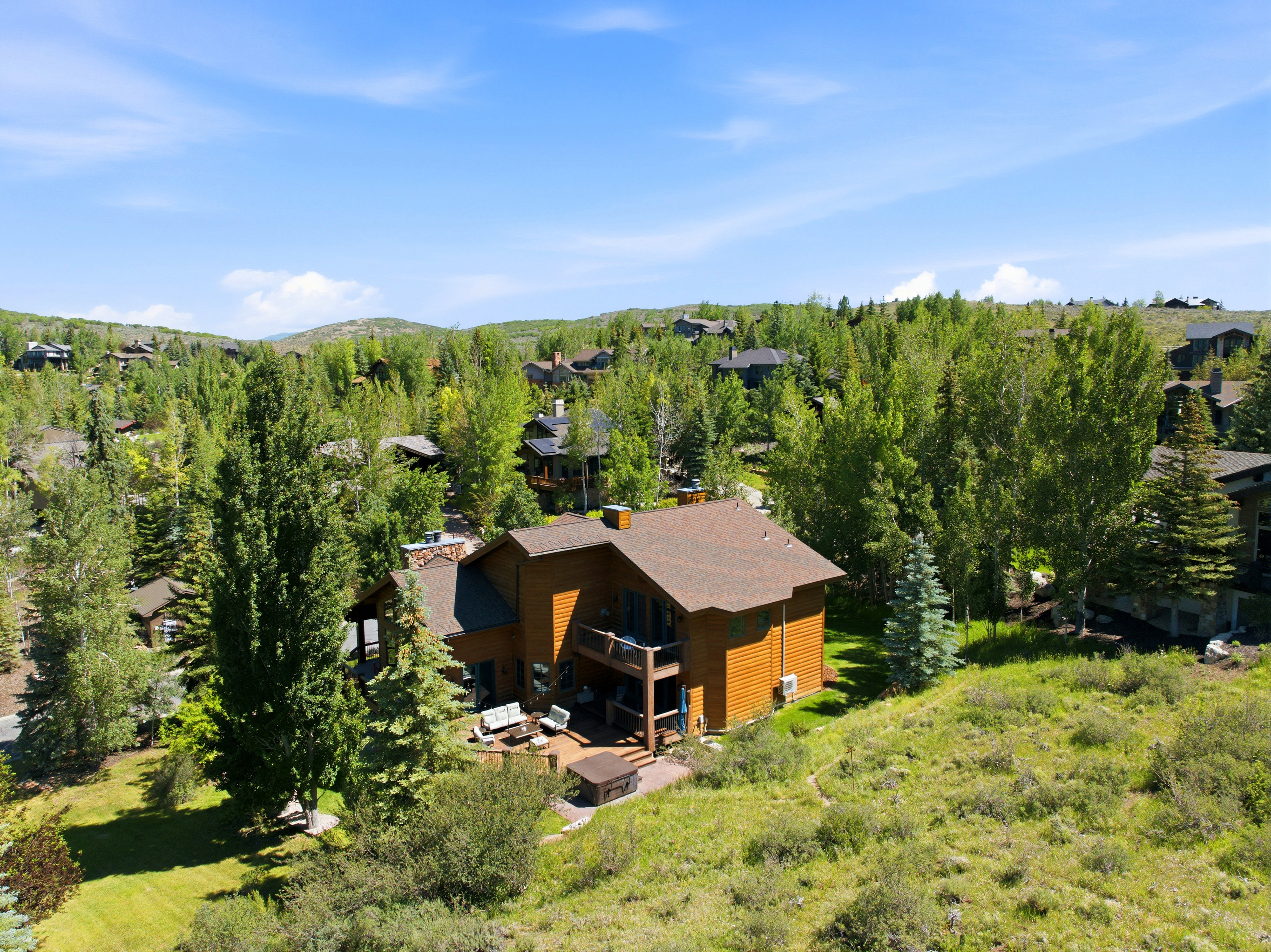 Multi-level residential property with rich wood-finish siding and a dark shingle roof