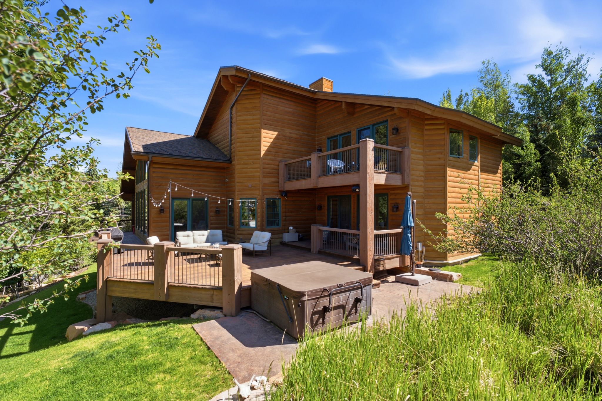 Wood-sided home featuring a multi-level deck and stone patio