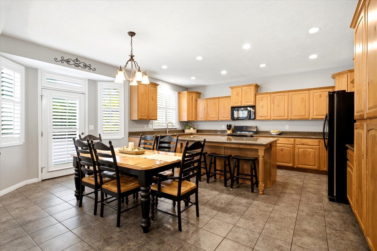 Spacious kitchen featuring light wood cabinetry, stone countertops, and a central island with bar seating