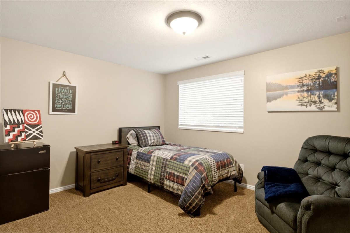 Carpeted room featuring a single window with blinds, a built-in overhead light fixture, light-toned walls, and white baseboards