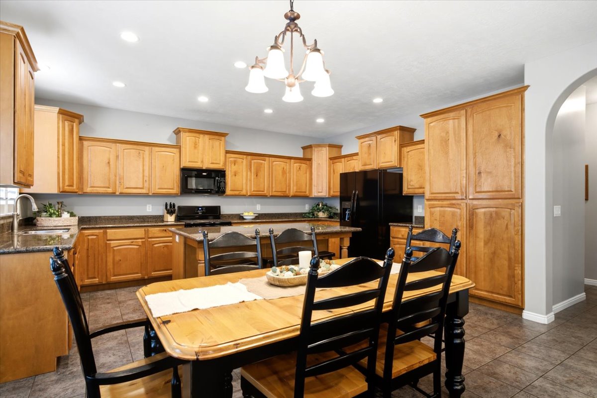 Kitchen featuring abundant cabinetry, dark countertops, built-in black appliances, recessed lighting, and tile flooring
