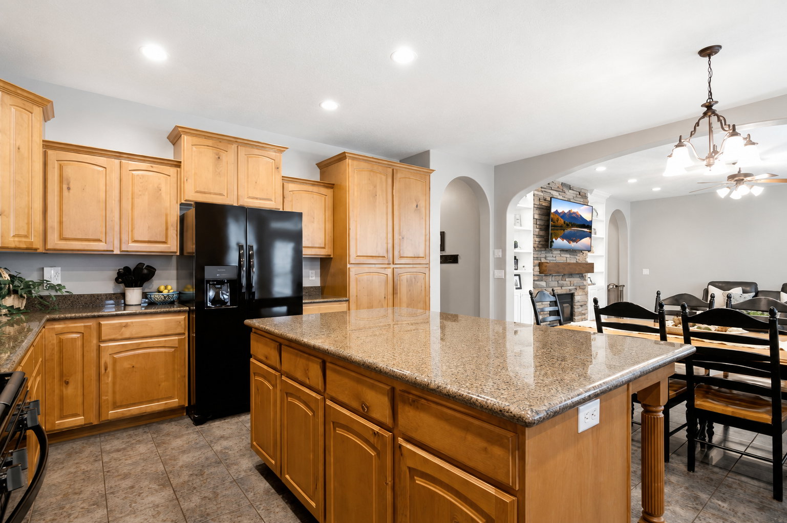 Kitchen featuring a large central island with a stone-finish countertop, light wood cabinetry, recessed lighting, and tile flooring