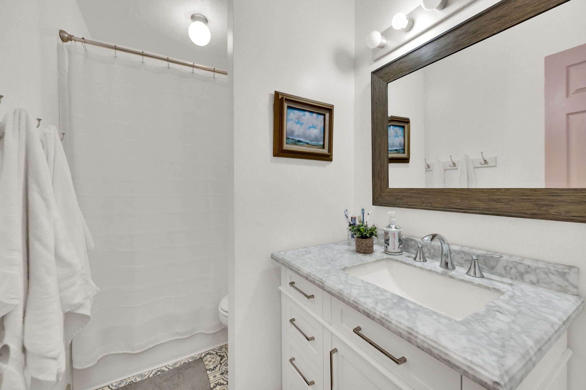 Bathroom vanity featuring a light marble countertop with undermount sink and chrome fixtures