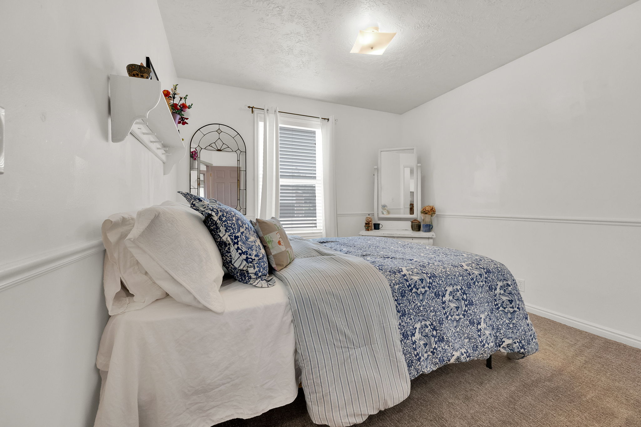 Carpeted room featuring white walls, wainscoting, and a window with blinds