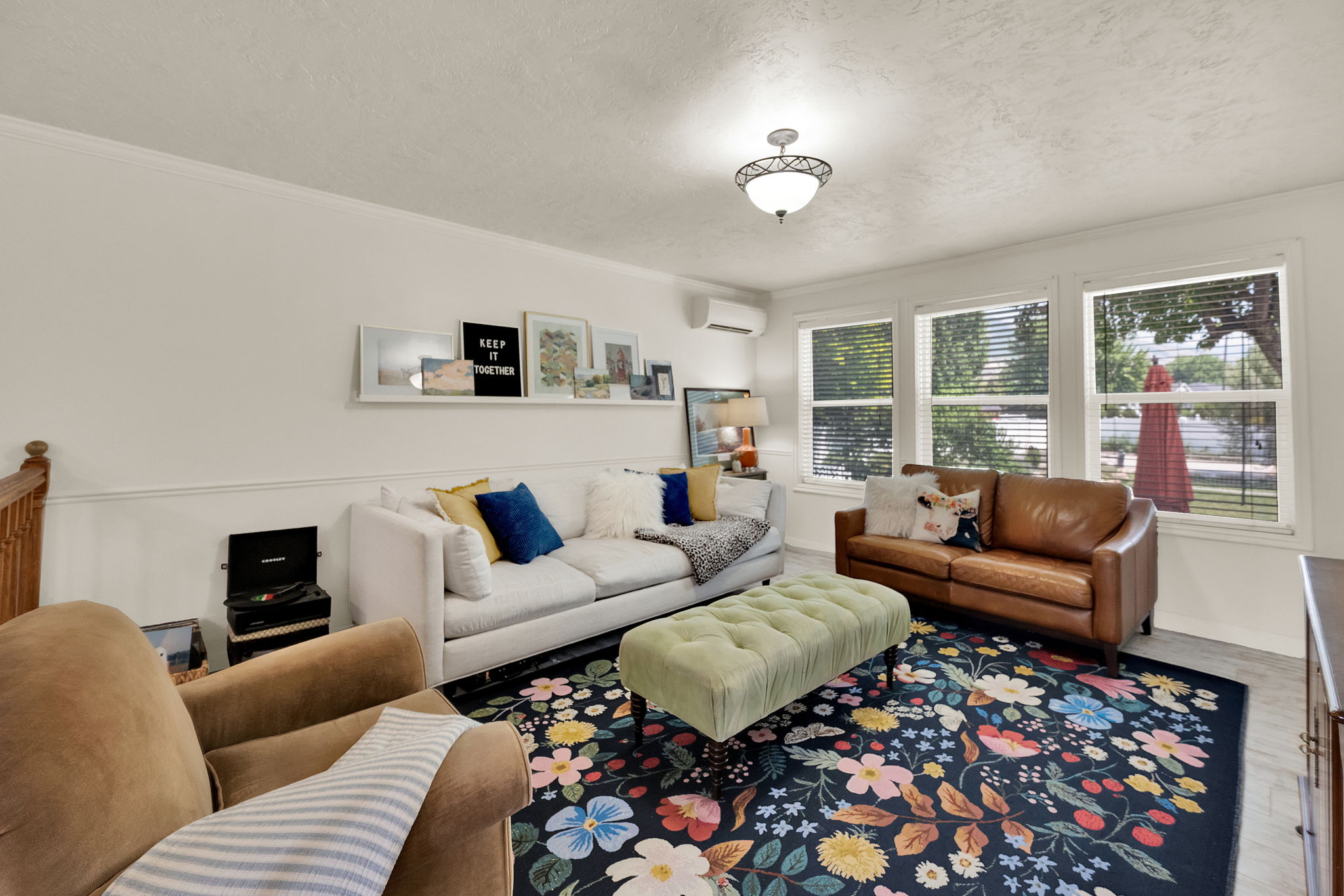 Living area featuring white walls, chair rail molding, and multiple windows with blinds