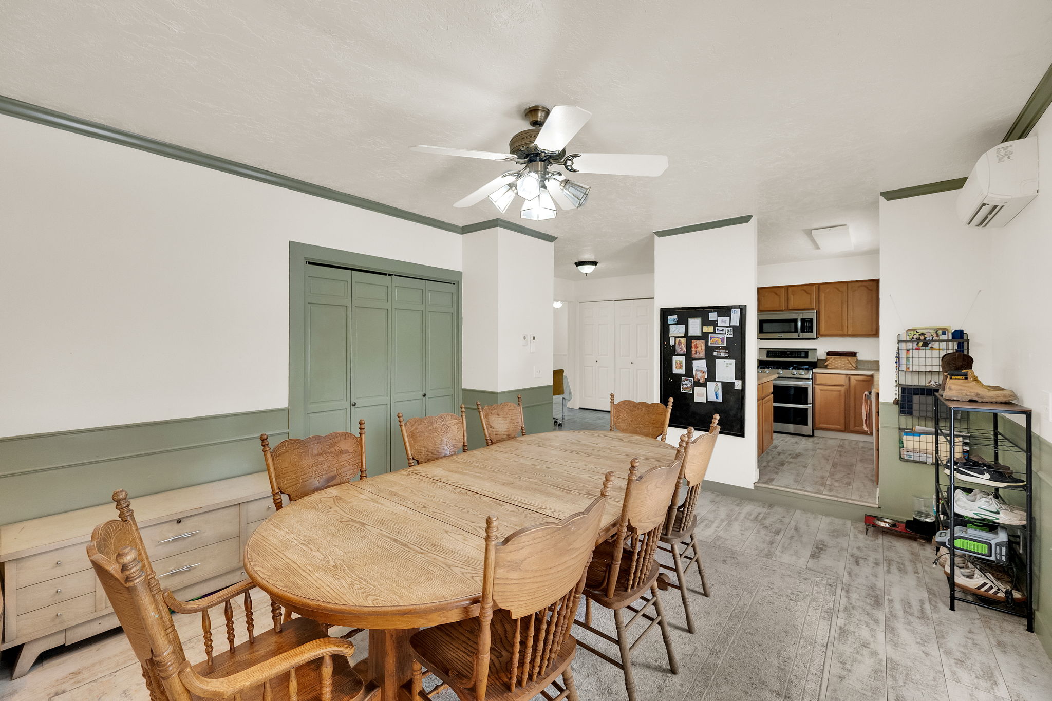 Dining area featuring wood-finish flooring, two-tone walls with wainscoting and crown molding, and a ceiling fan with integrated lighting