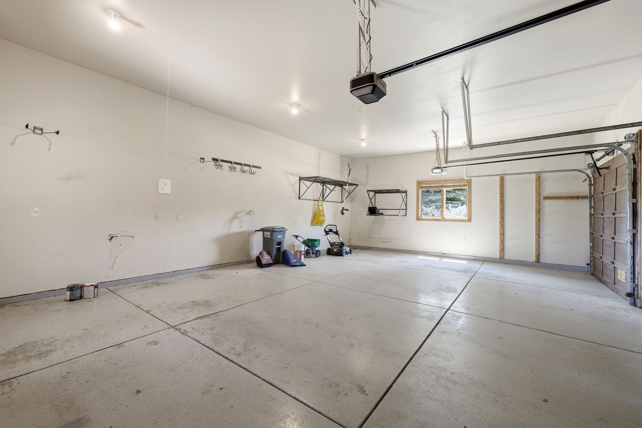 Spacious garage with concrete flooring, recessed lighting, a paneled garage door, and a single window with wood trim