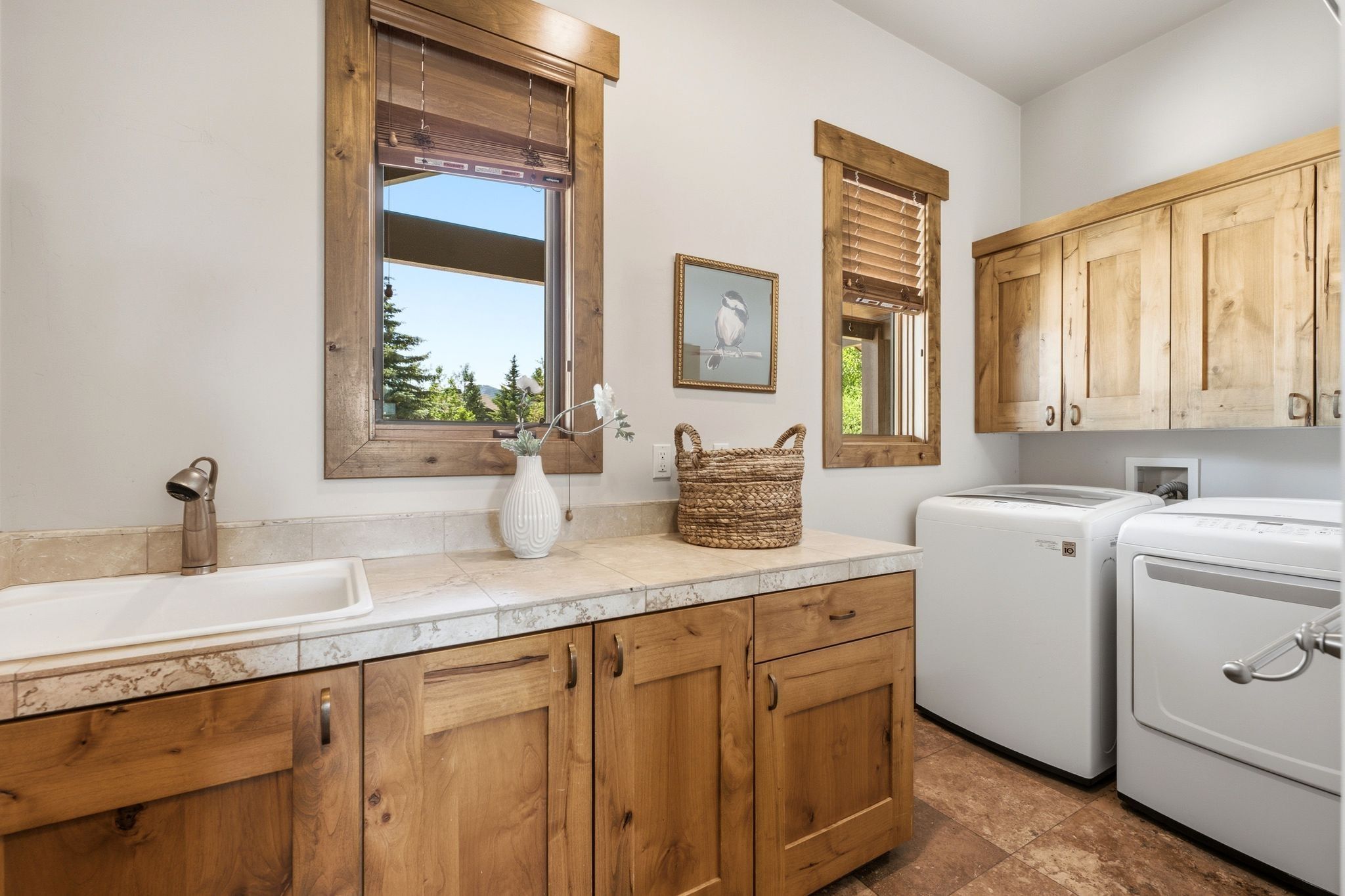 Laundry room with wood cabinetry, tiled countertops, an integrated utility sink, and a tiled floor