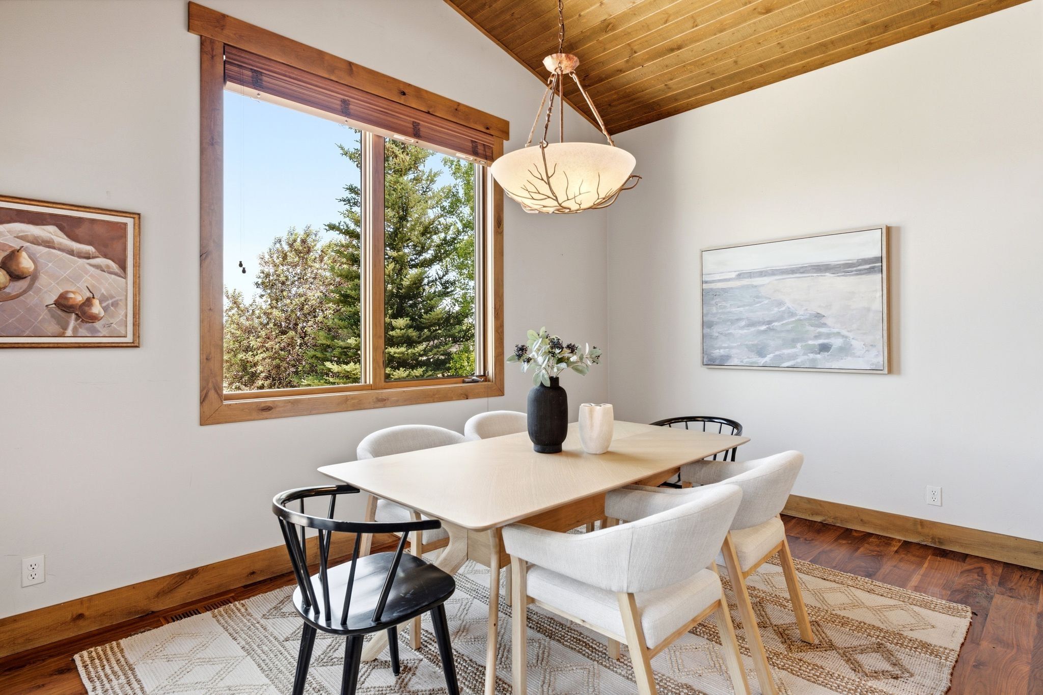 Vaulted wood-finish ceiling above a spacious room featuring a large window with wood trim, wood-finish flooring, and a unique overhead light fixture
