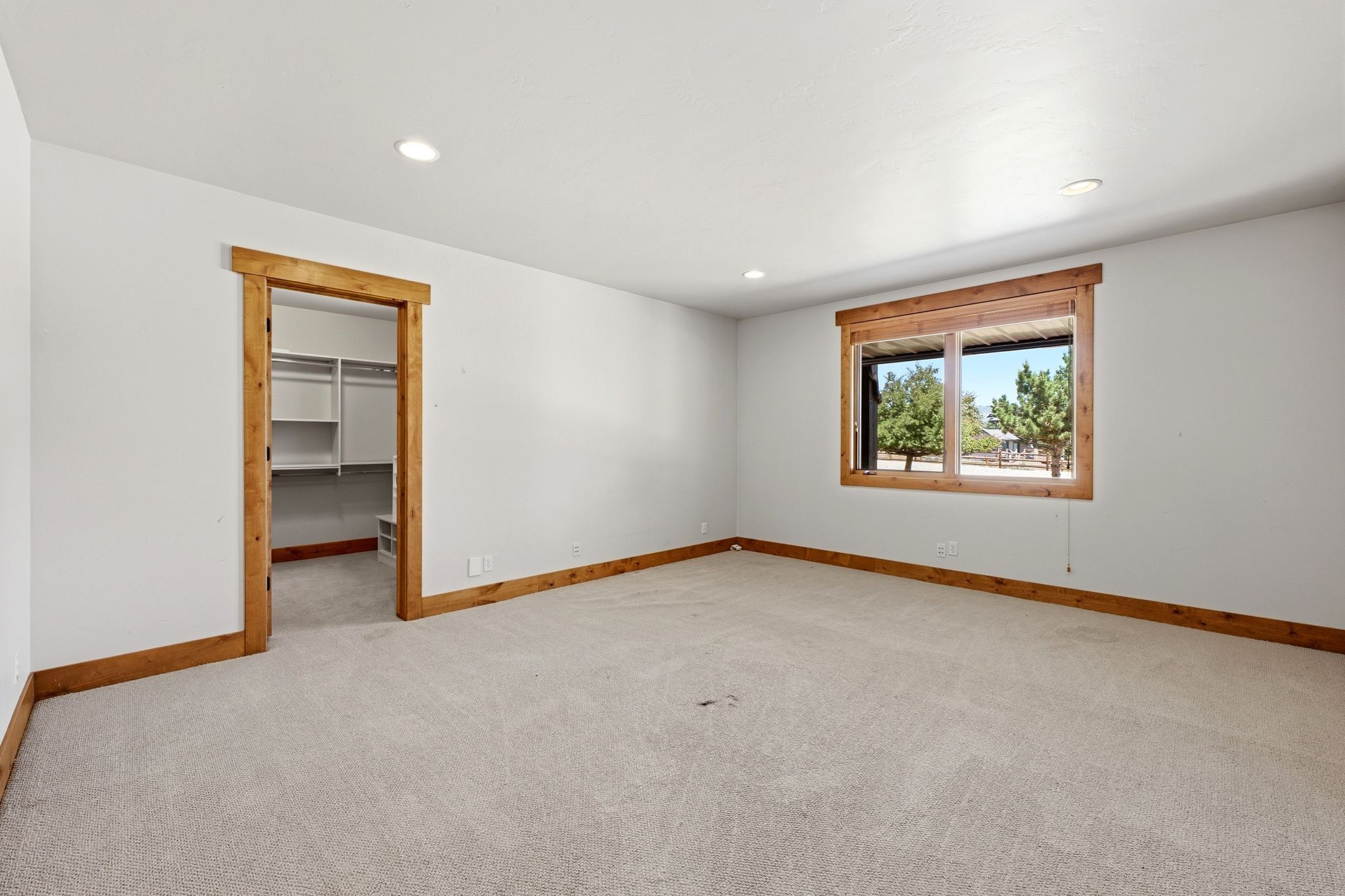 Spacious room featuring light-toned carpet flooring, white walls, and recessed lighting