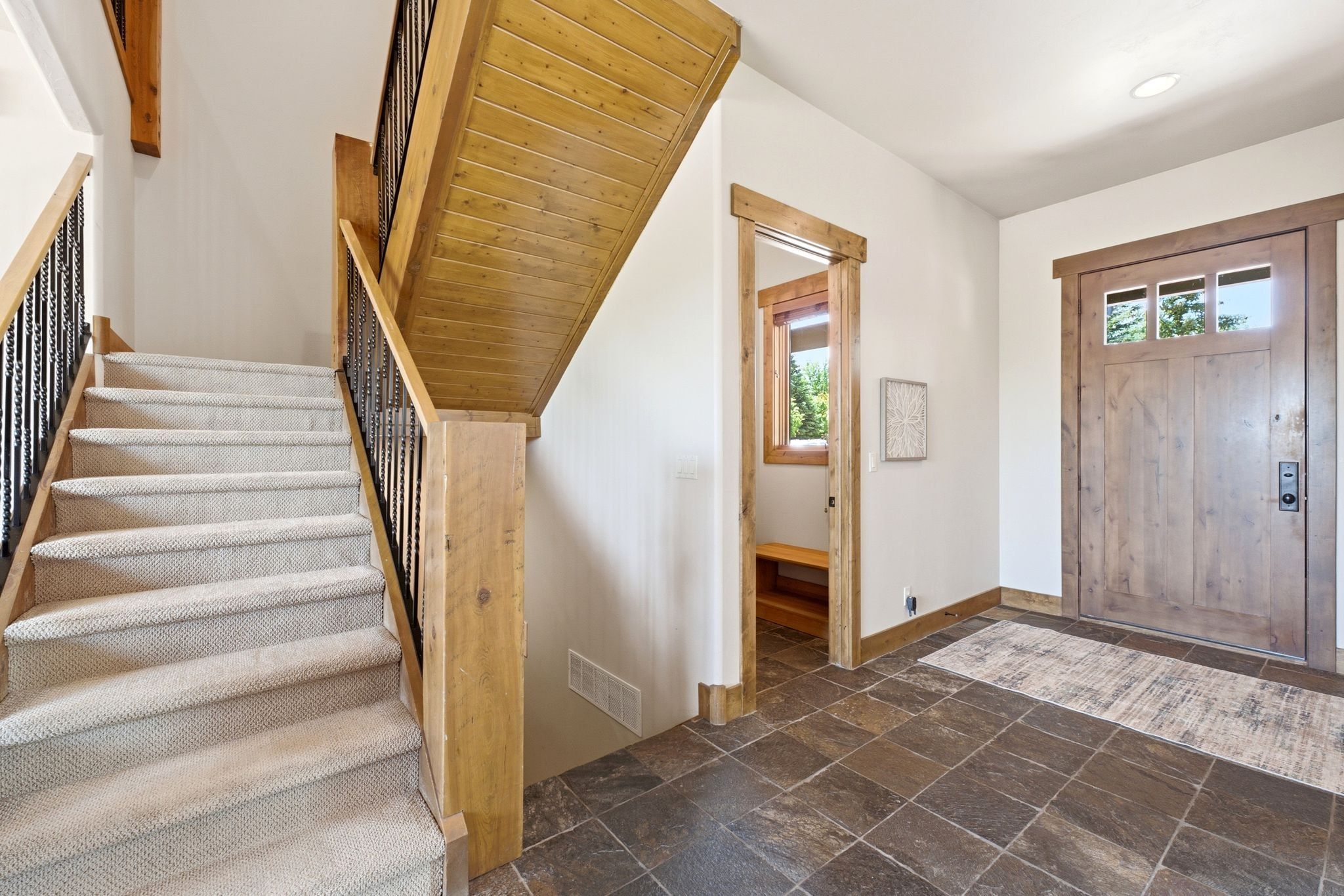 Entryway featuring dark slate-style tile flooring, a solid wood entry door with upper window panes, and wood trim detailing