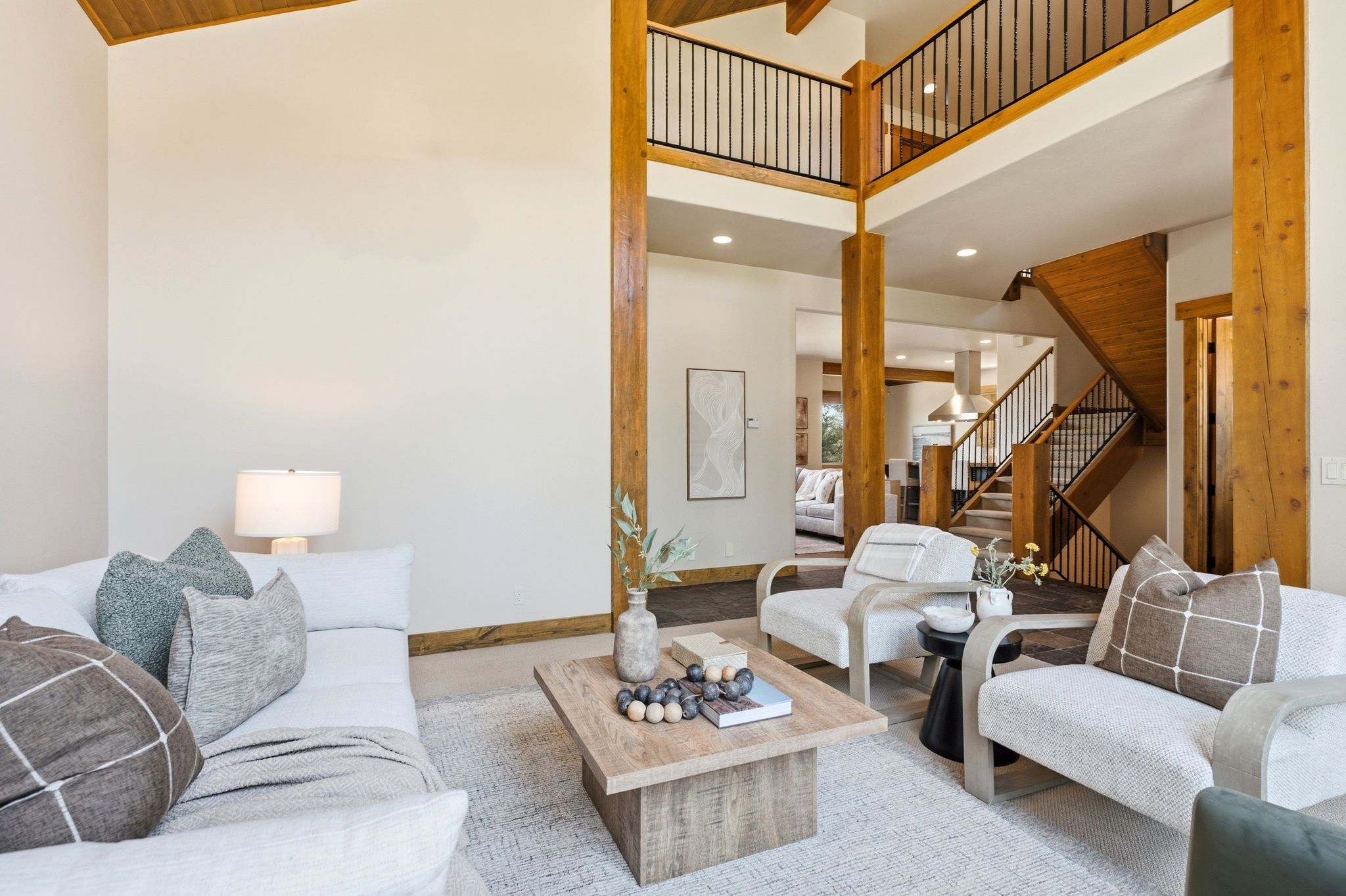 Vaulted living area featuring exposed wood beams and a dual-level interior balcony with wrought iron railing