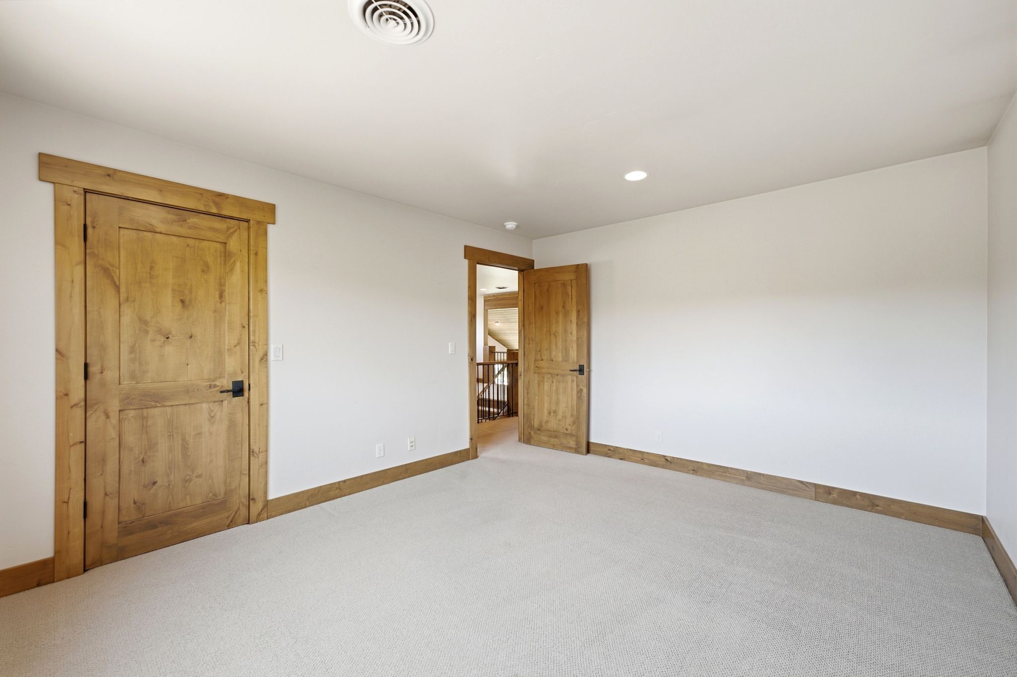 Neutral carpet flooring complemented by white walls and recessed lighting