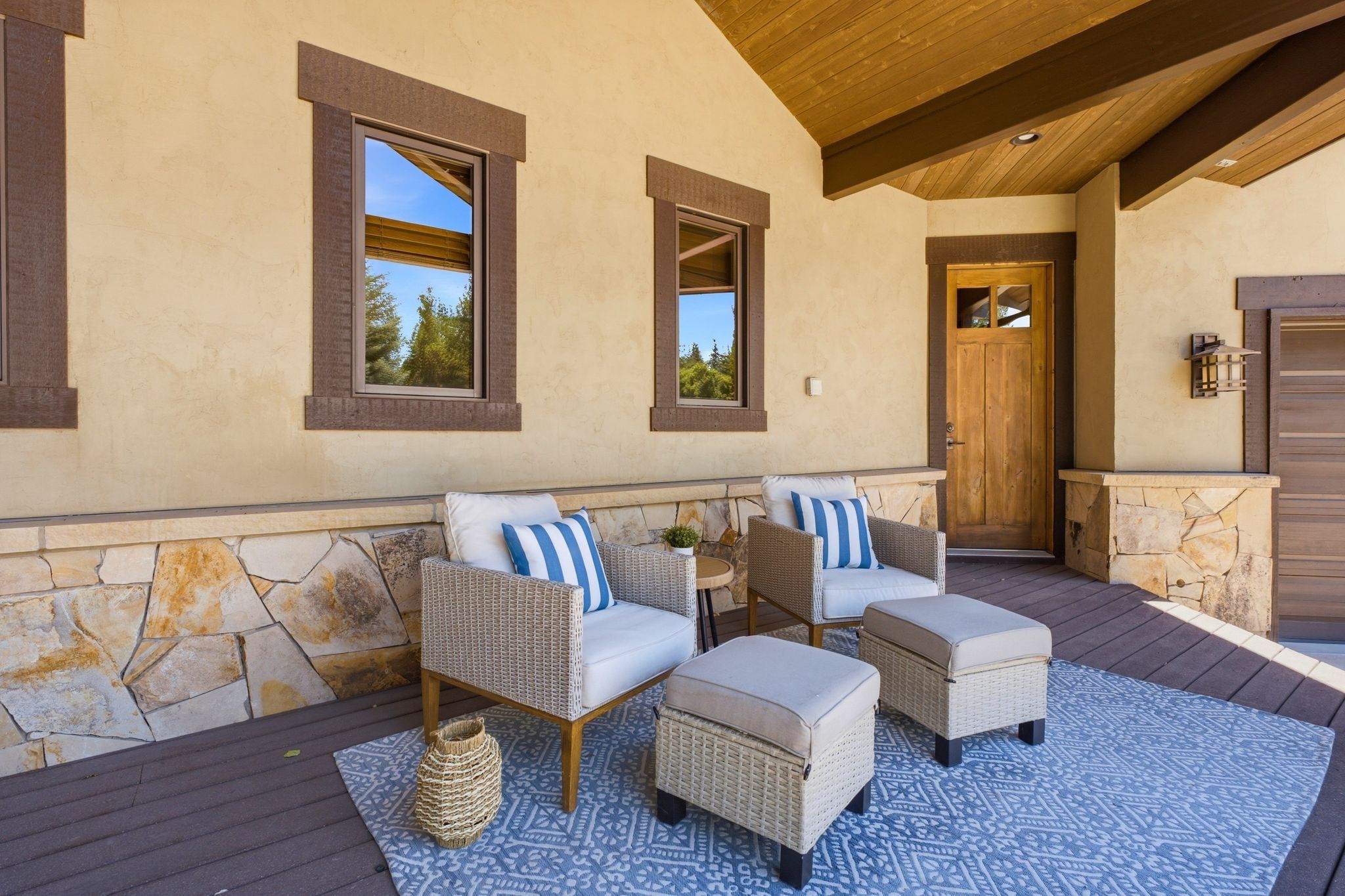 Covered patio featuring stone accents, a wood-paneled ceiling with exposed beams, wood-finish flooring, and a solid wood entry door