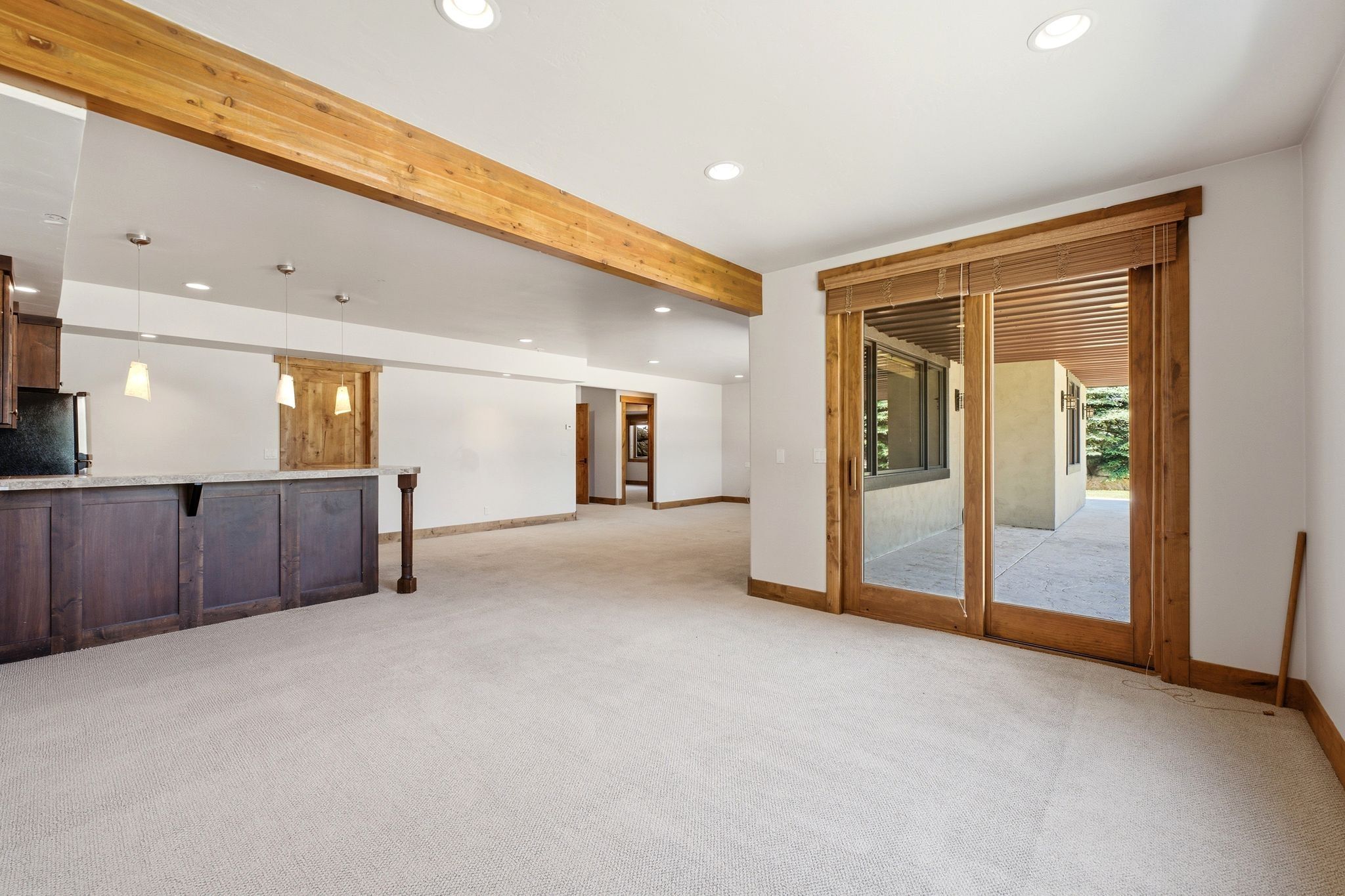 Spacious room featuring light-colored carpeting and a wood-beamed ceiling