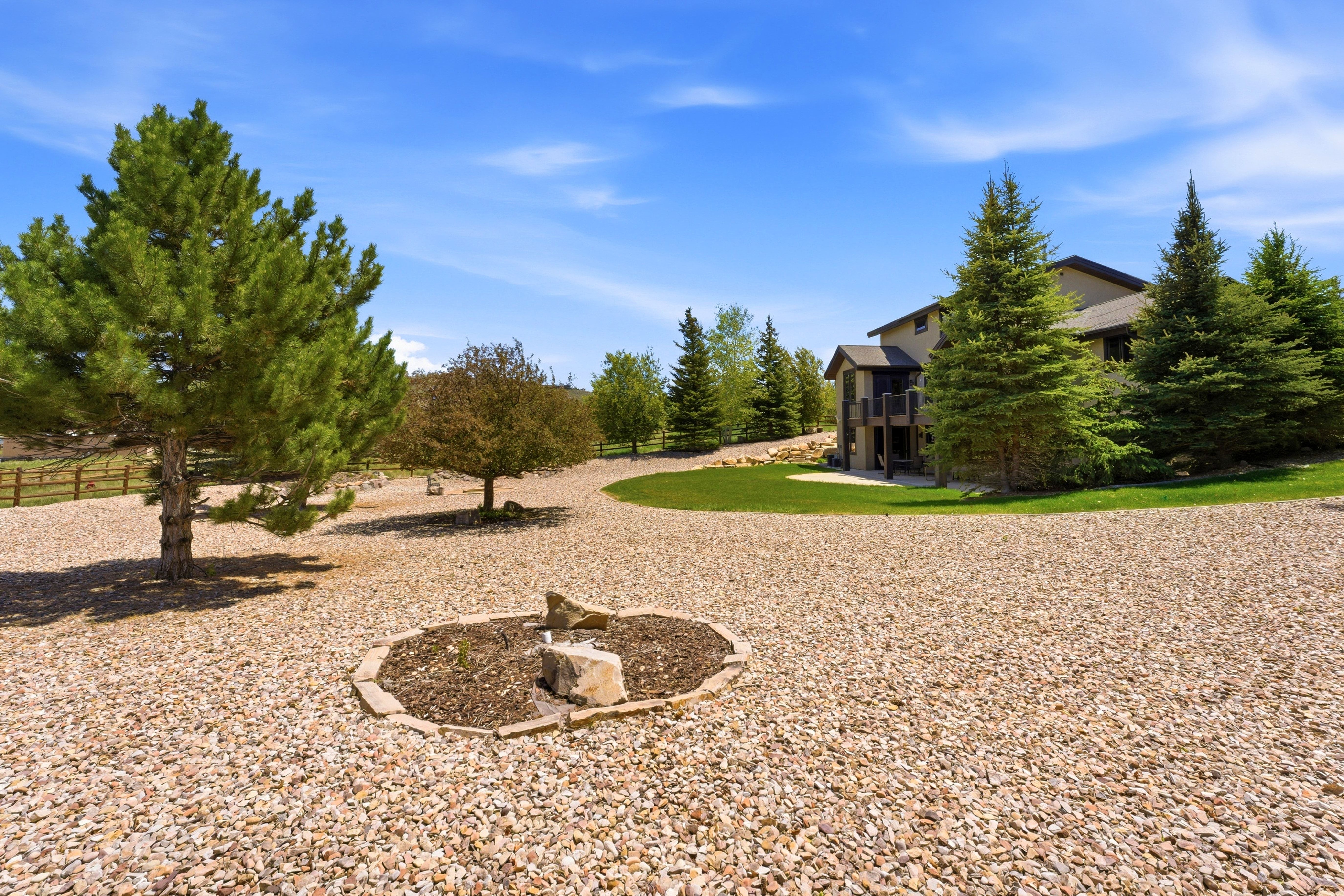 Expansive gravel driveway featuring a central planting bed with natural stone accents