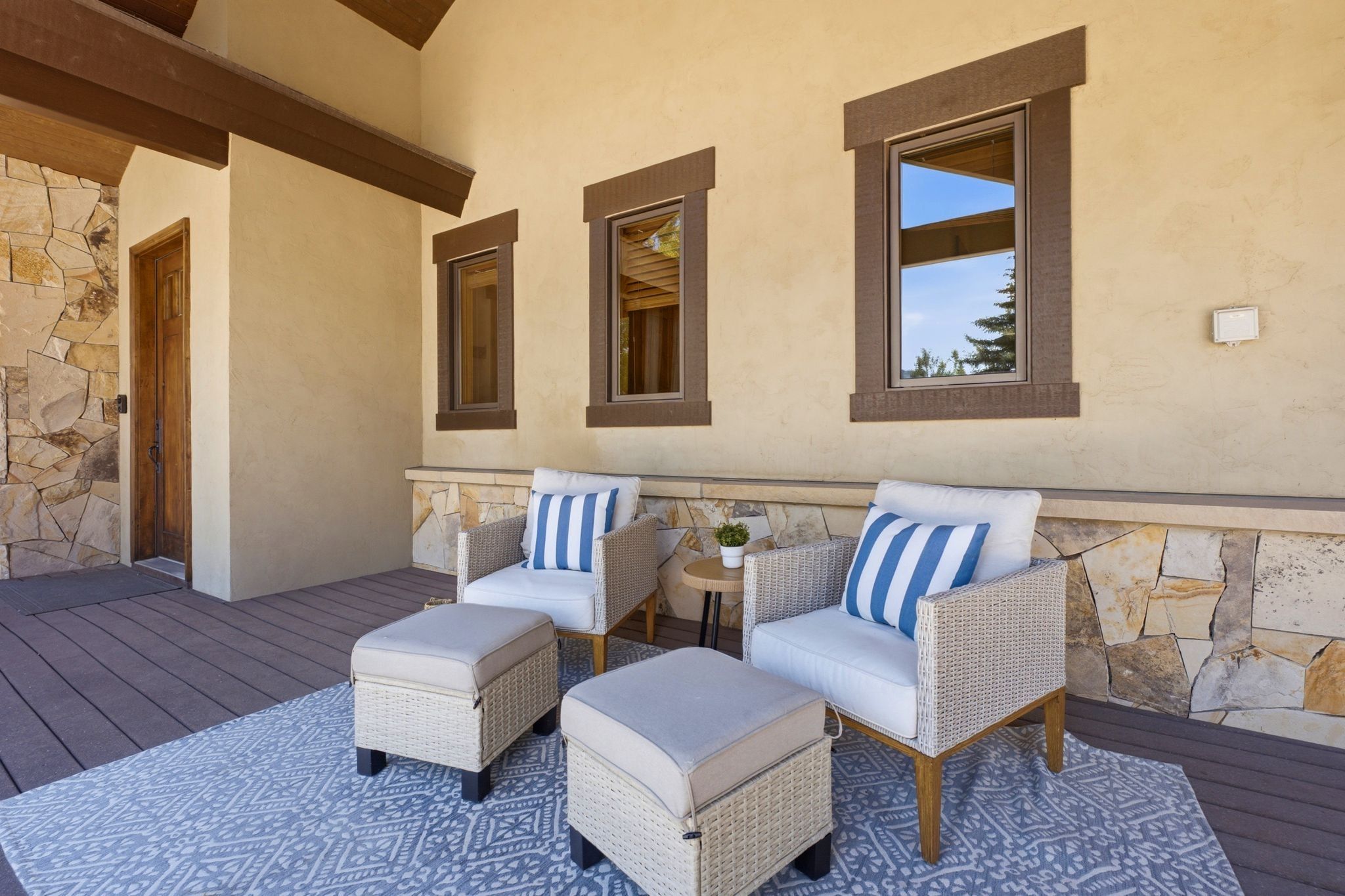 Covered outdoor patio featuring stone veneer, stucco siding, and dark wood-finish decking