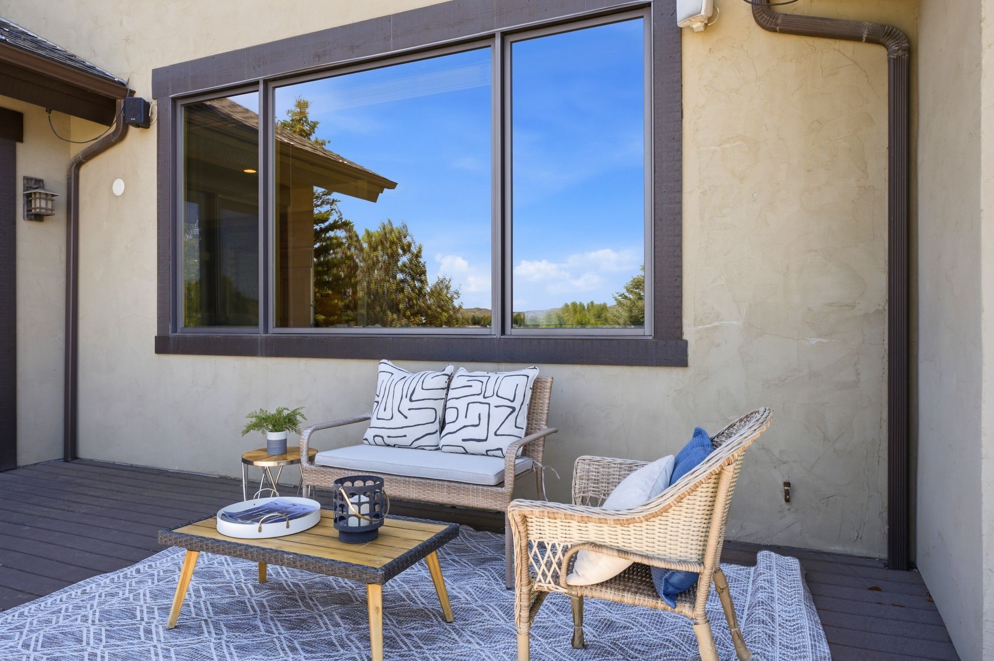 Private outdoor deck featuring a stucco exterior, dark-framed window, and composite decking