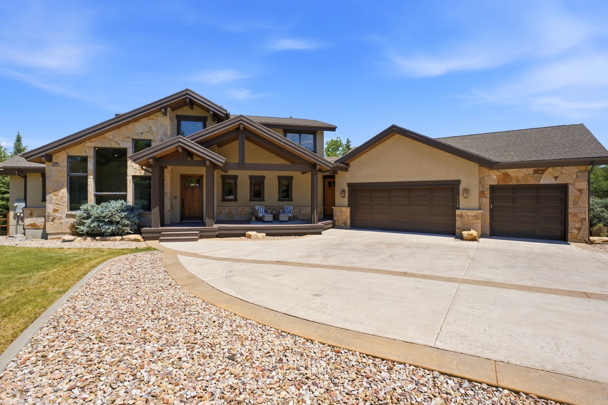 Stone and stucco exterior with multiple gables and a covered front porch