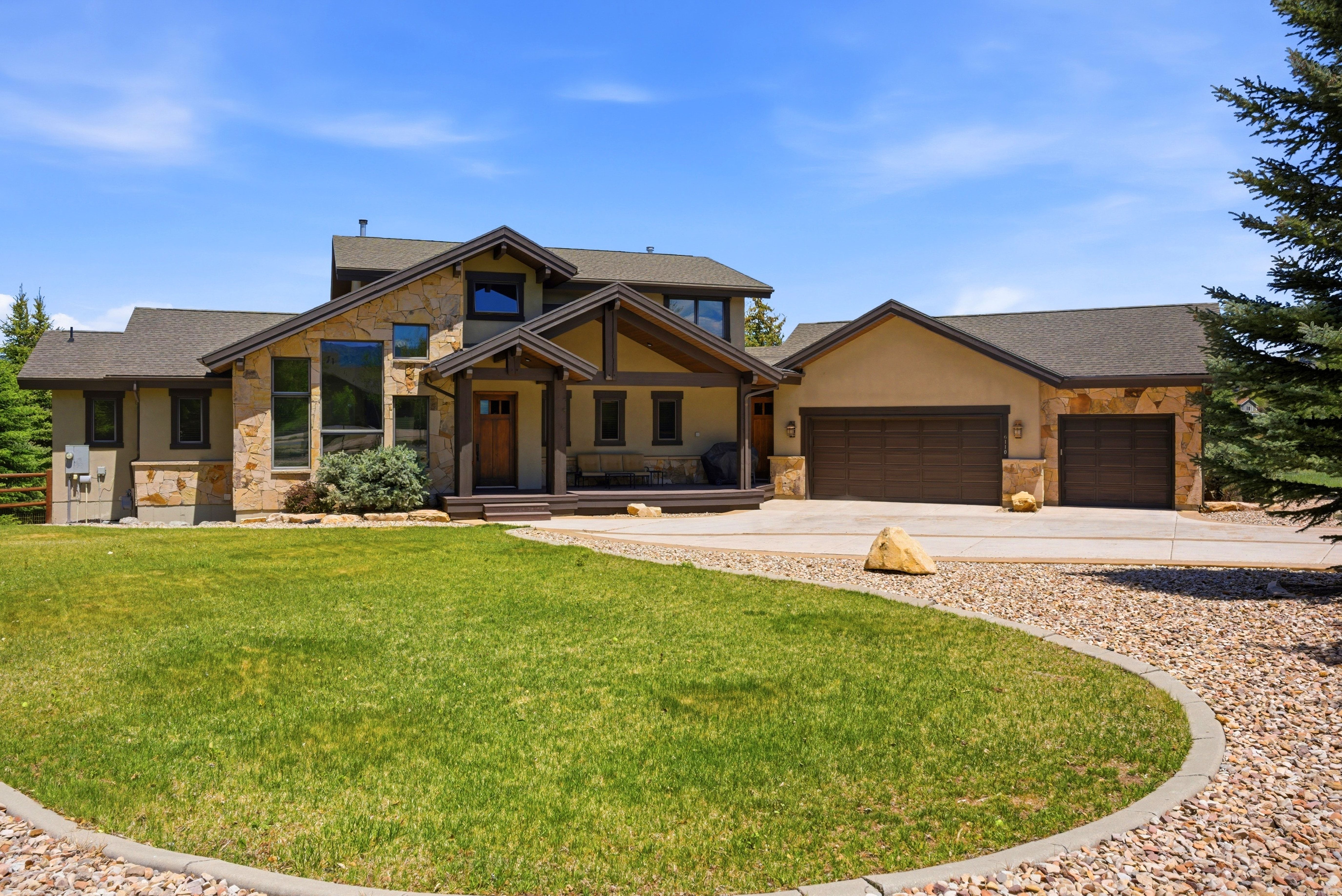 Stone and stucco exterior featuring multiple gables and a covered porch entry