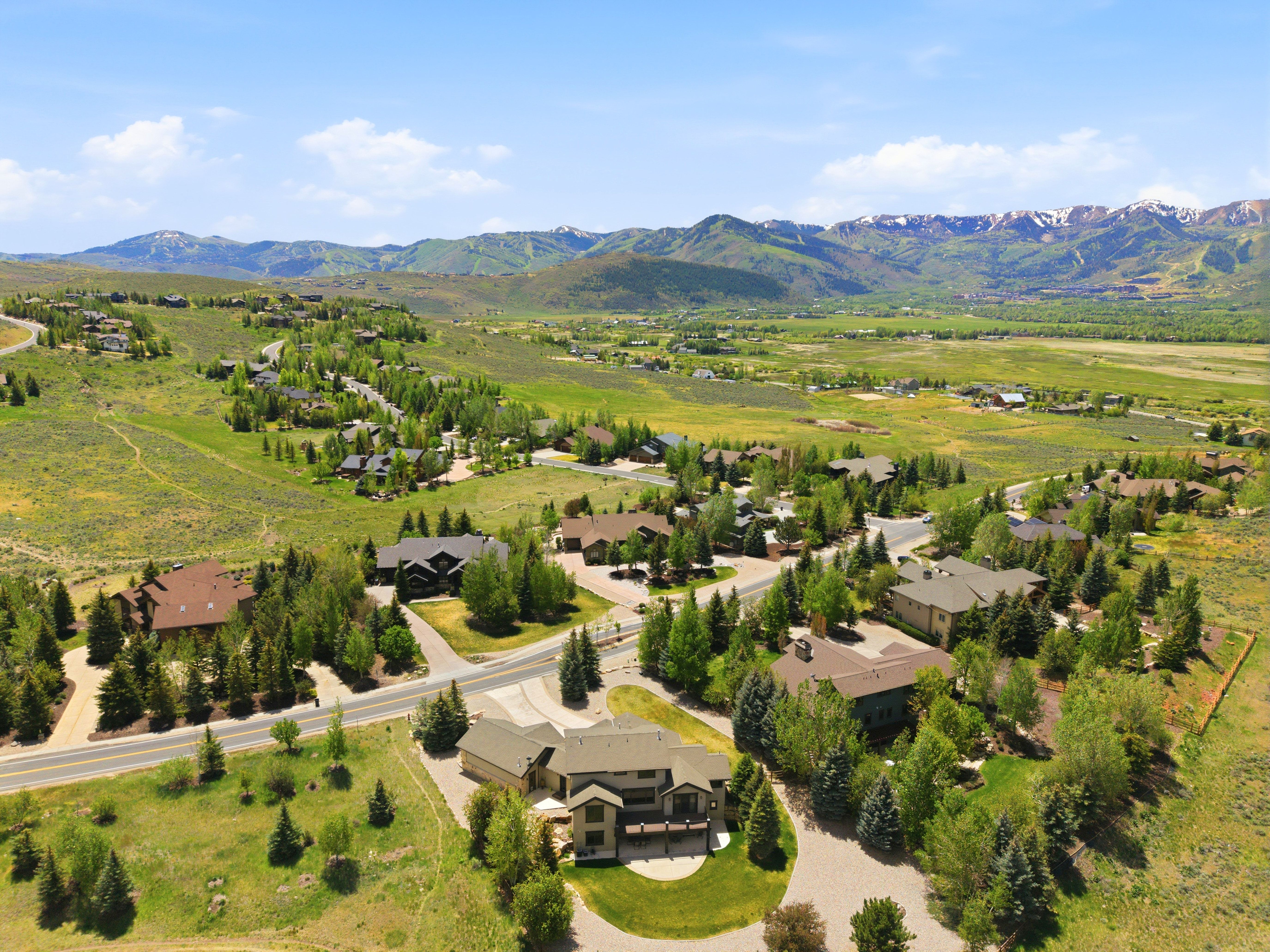 Expansive mountain landscape featuring a residential community with paved roads and mature trees