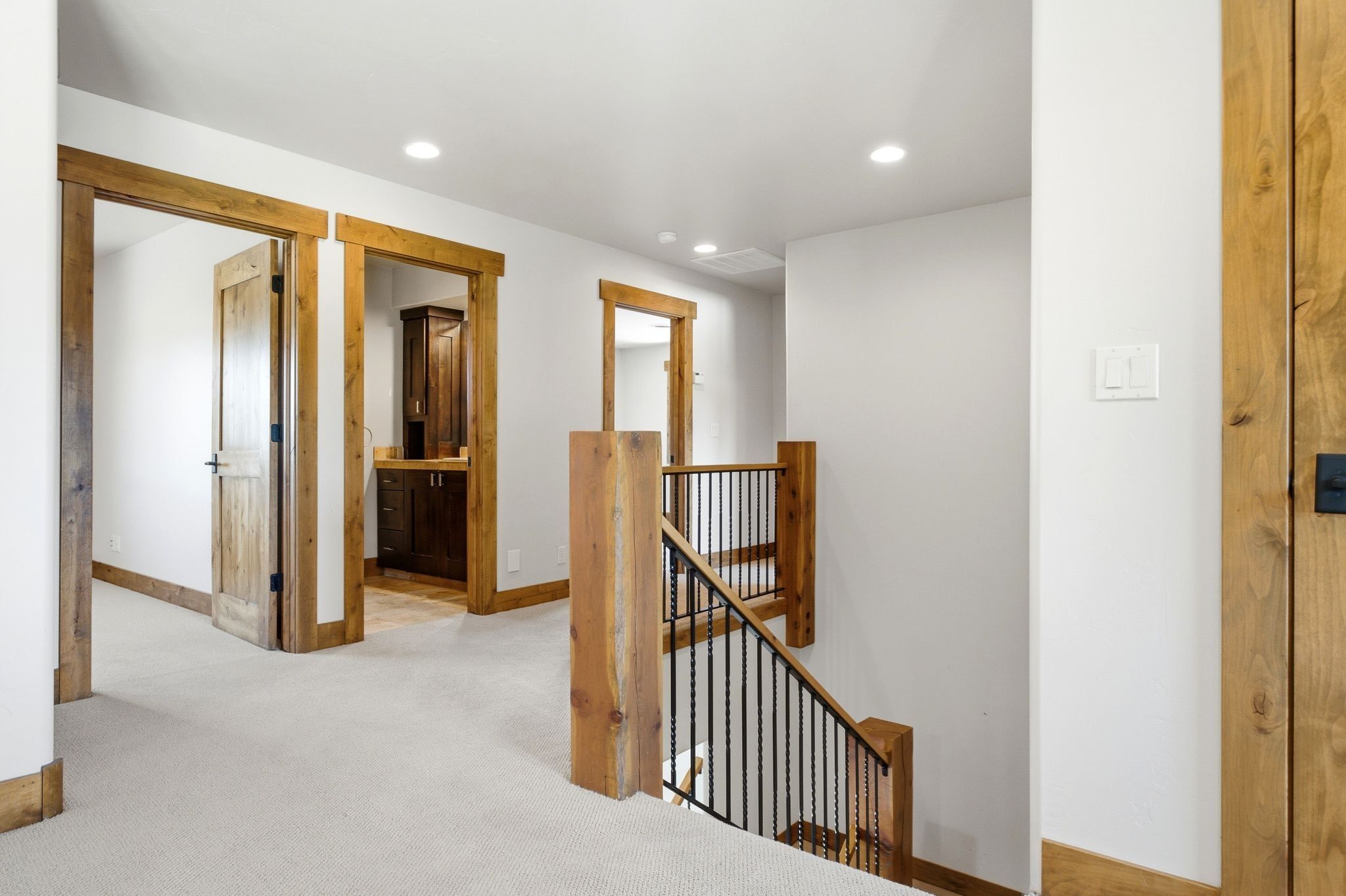 Upper level landing with light-toned carpeting and recessed lighting