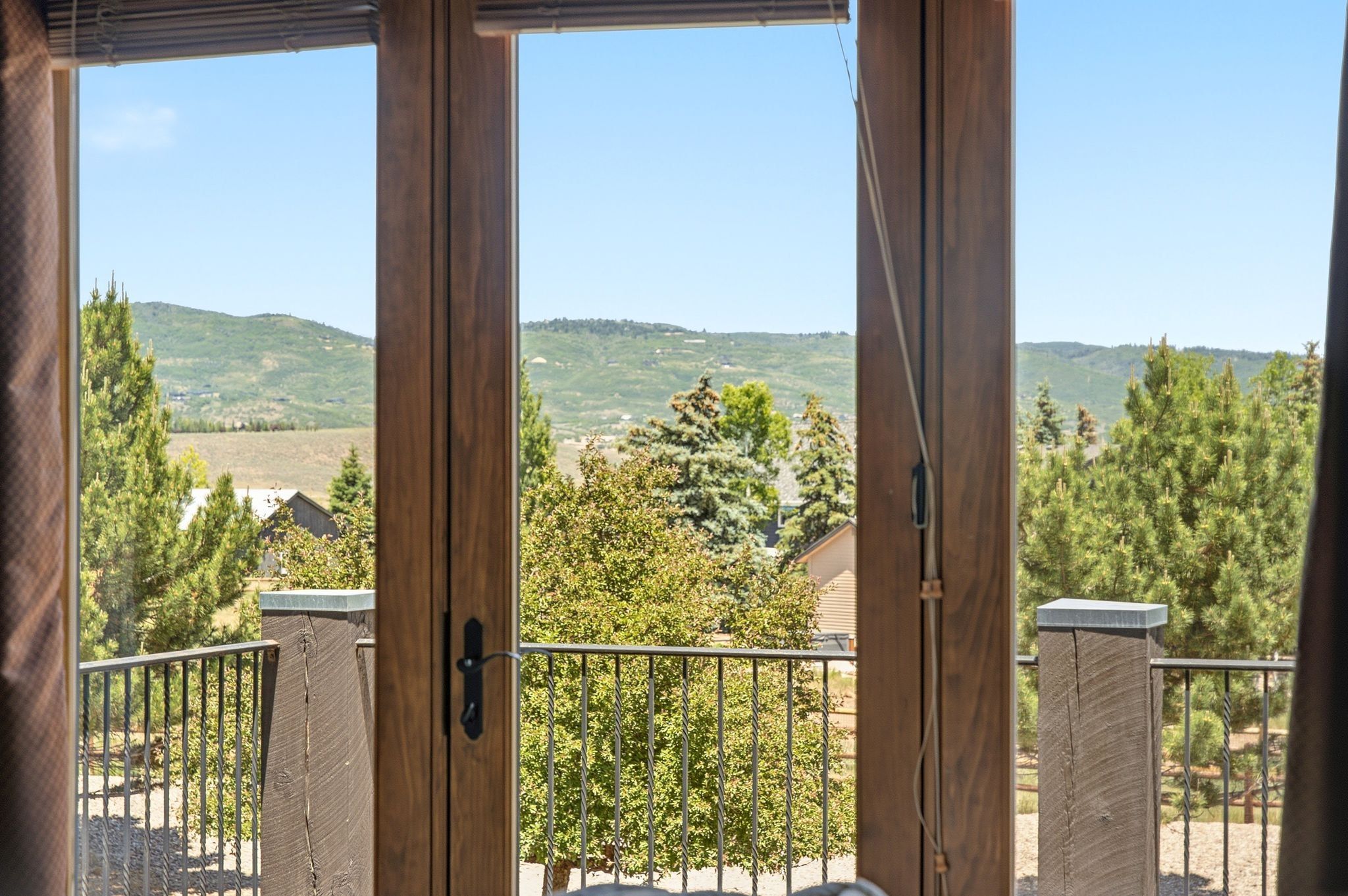 Wood-finish French doors open to an outdoor balcony with a metal railing