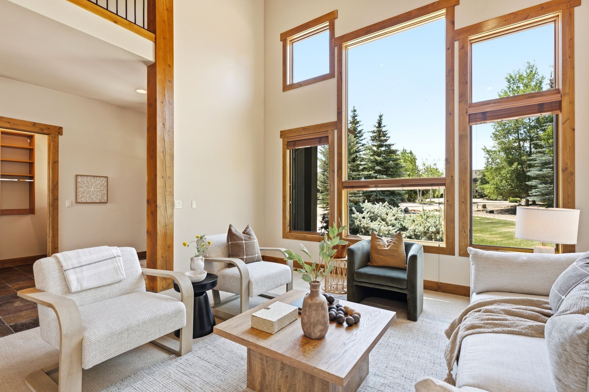 Spacious interior featuring soaring ceilings, abundant natural light, exposed wood beams, and a combination of wood-finish and tile flooring