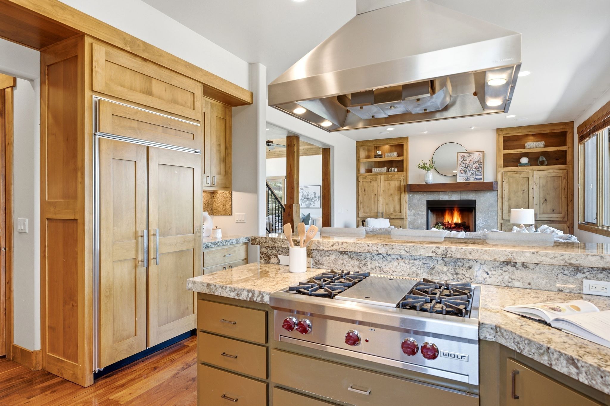 Kitchen featuring a built-in paneled refrigerator, integrated gas range, and a large stainless steel range hood