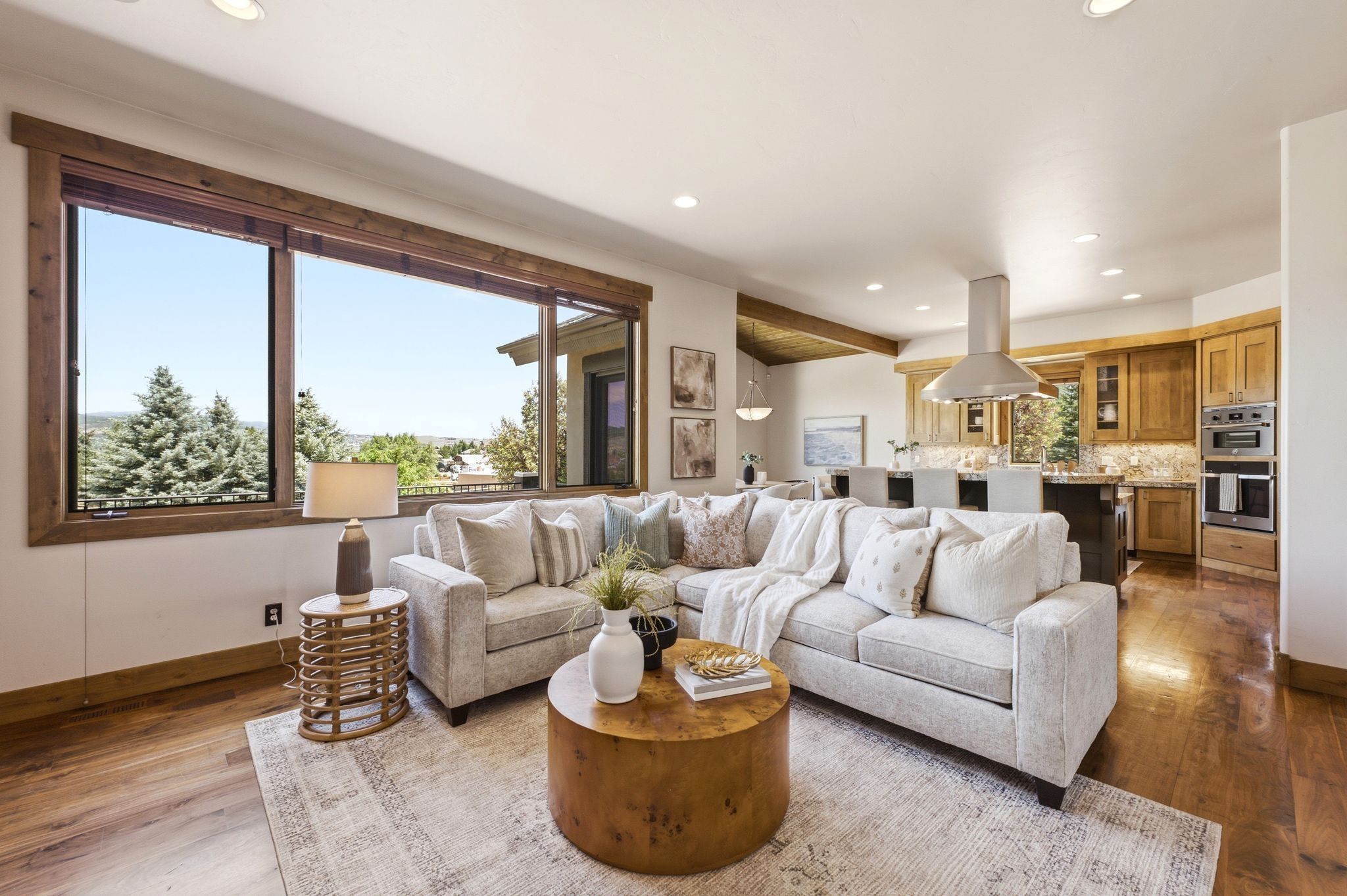 Open-concept living space featuring wood-finish flooring, recessed lighting, and expansive windows with natural wood trim