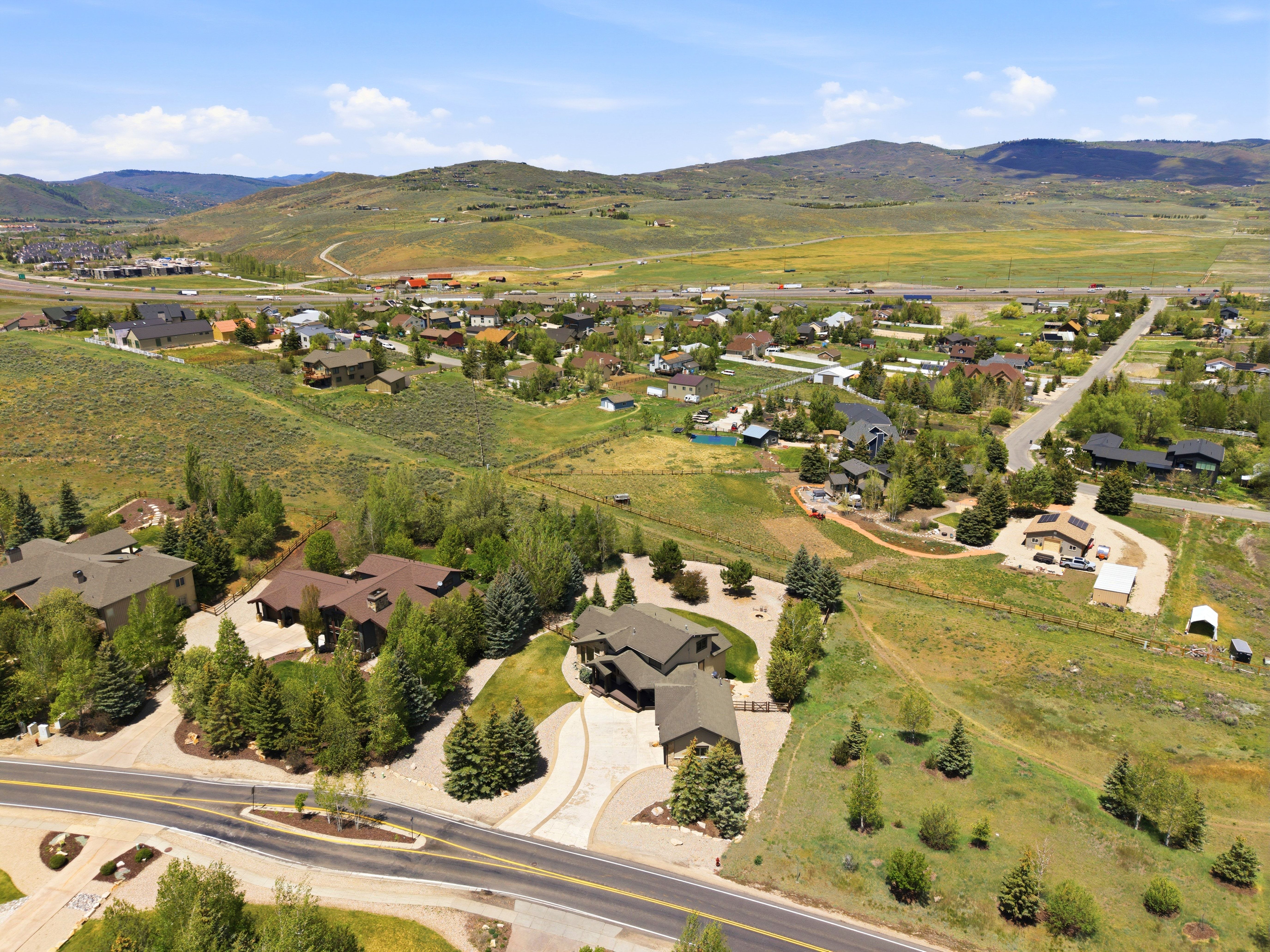 Expansive property featuring a large residence with a multi-car driveway, surrounded by mature trees and varied landscaping