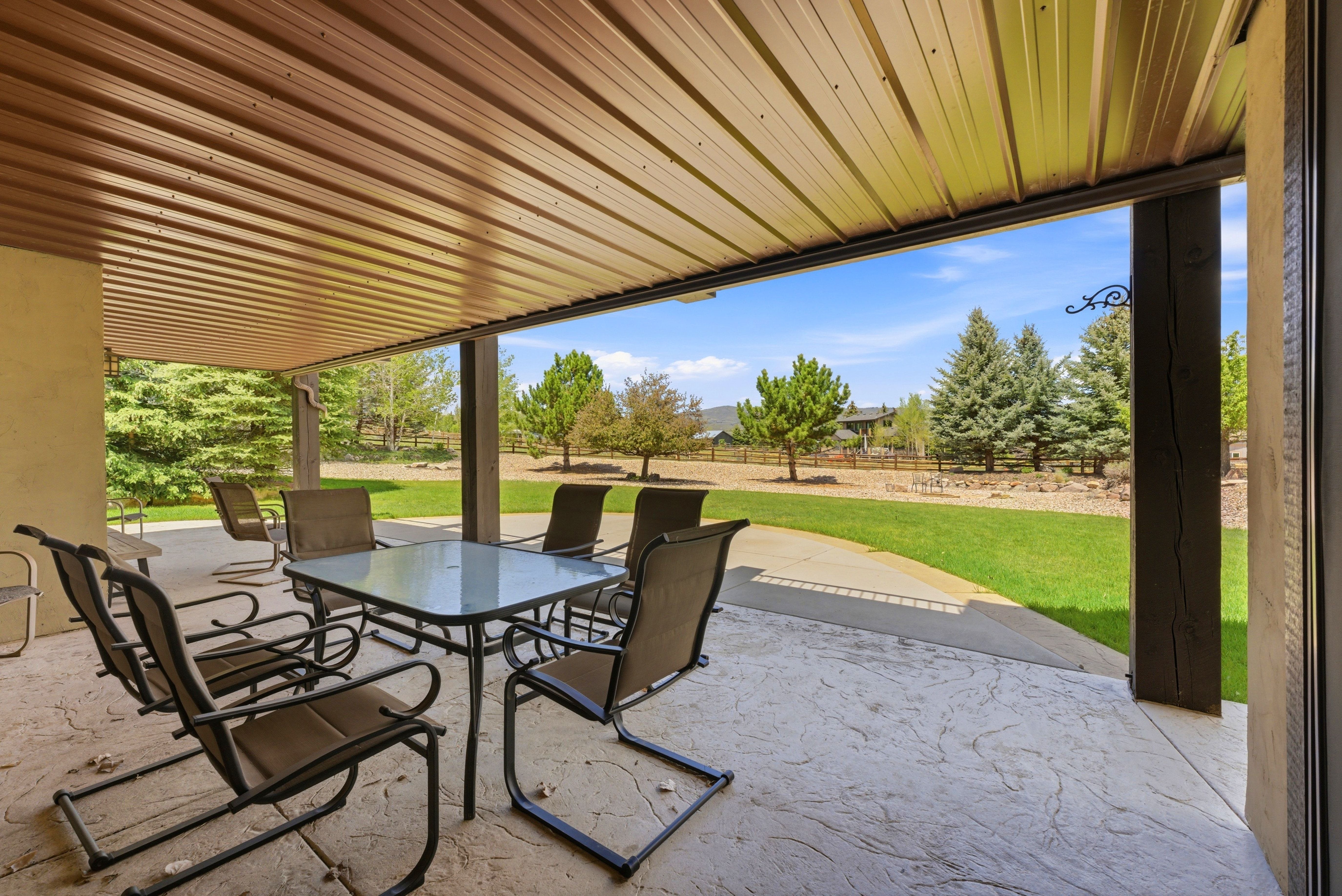Covered patio featuring a stamped concrete surface, a brown corrugated metal ceiling, and robust support columns