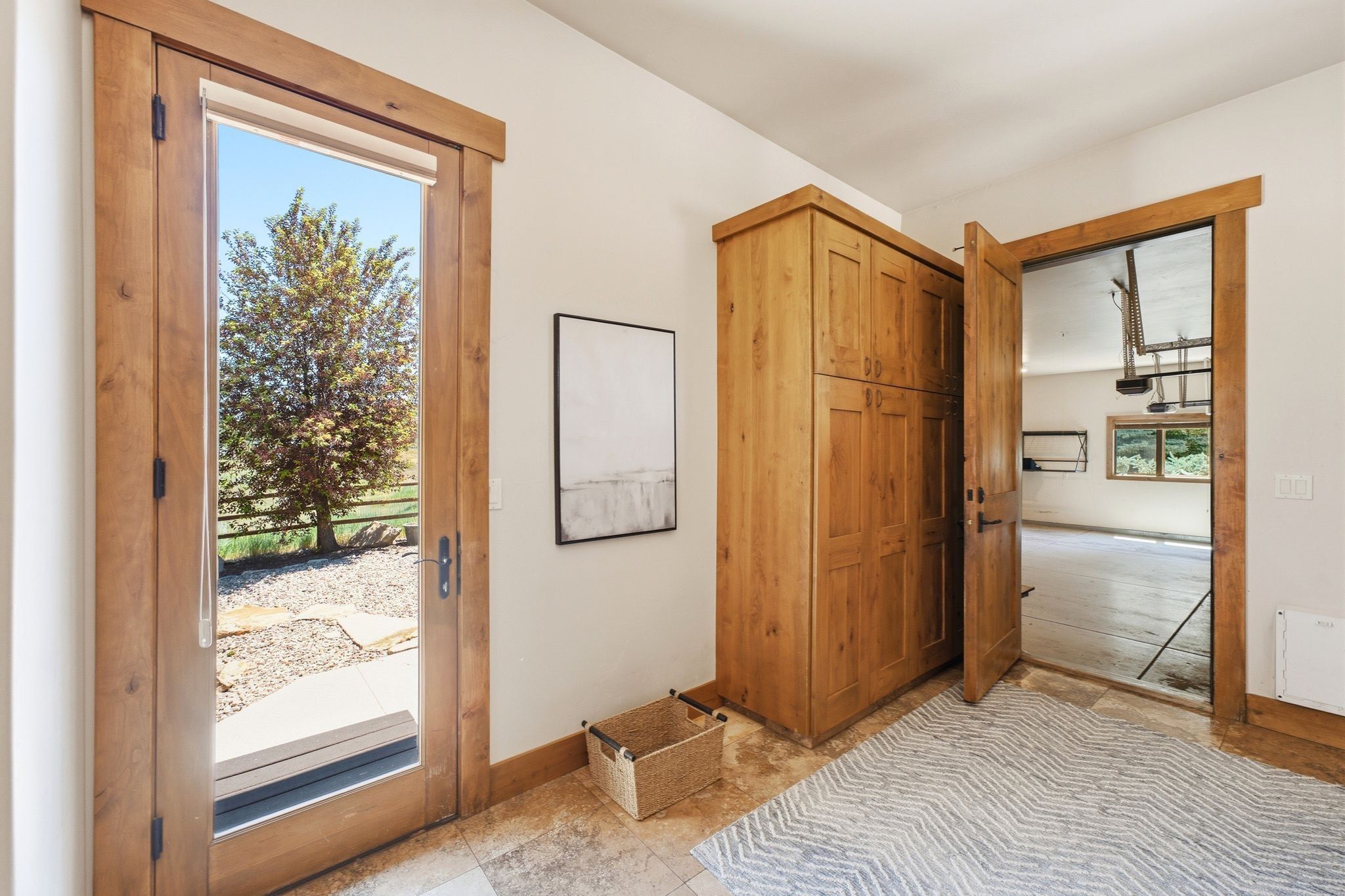 Entryway featuring a wood-framed glass-panel door, built-in wood cabinetry, and neutral-toned floor tile