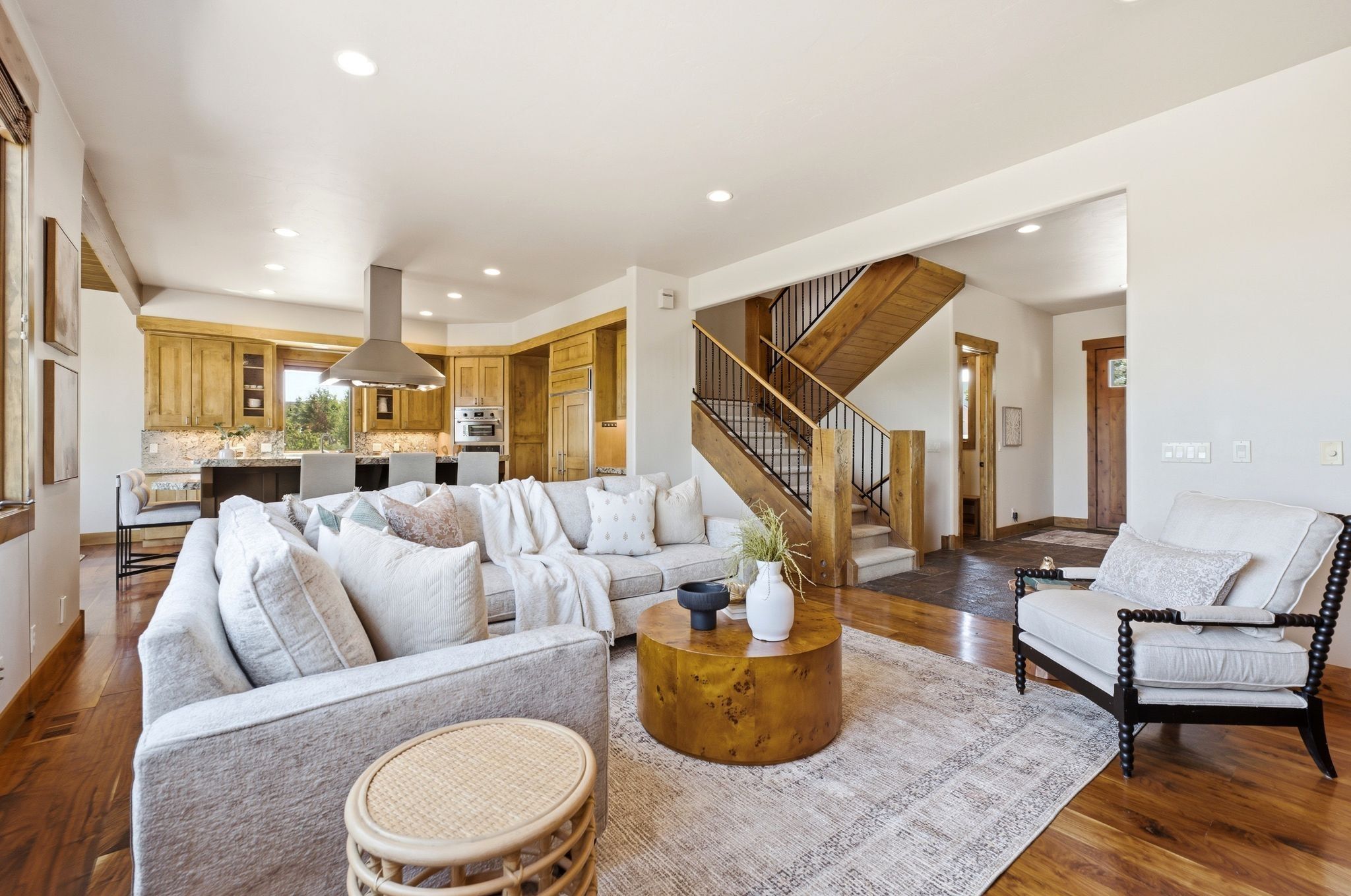 Expansive living area featuring wide plank wood-finish flooring, recessed lighting, and a custom wood and iron staircase