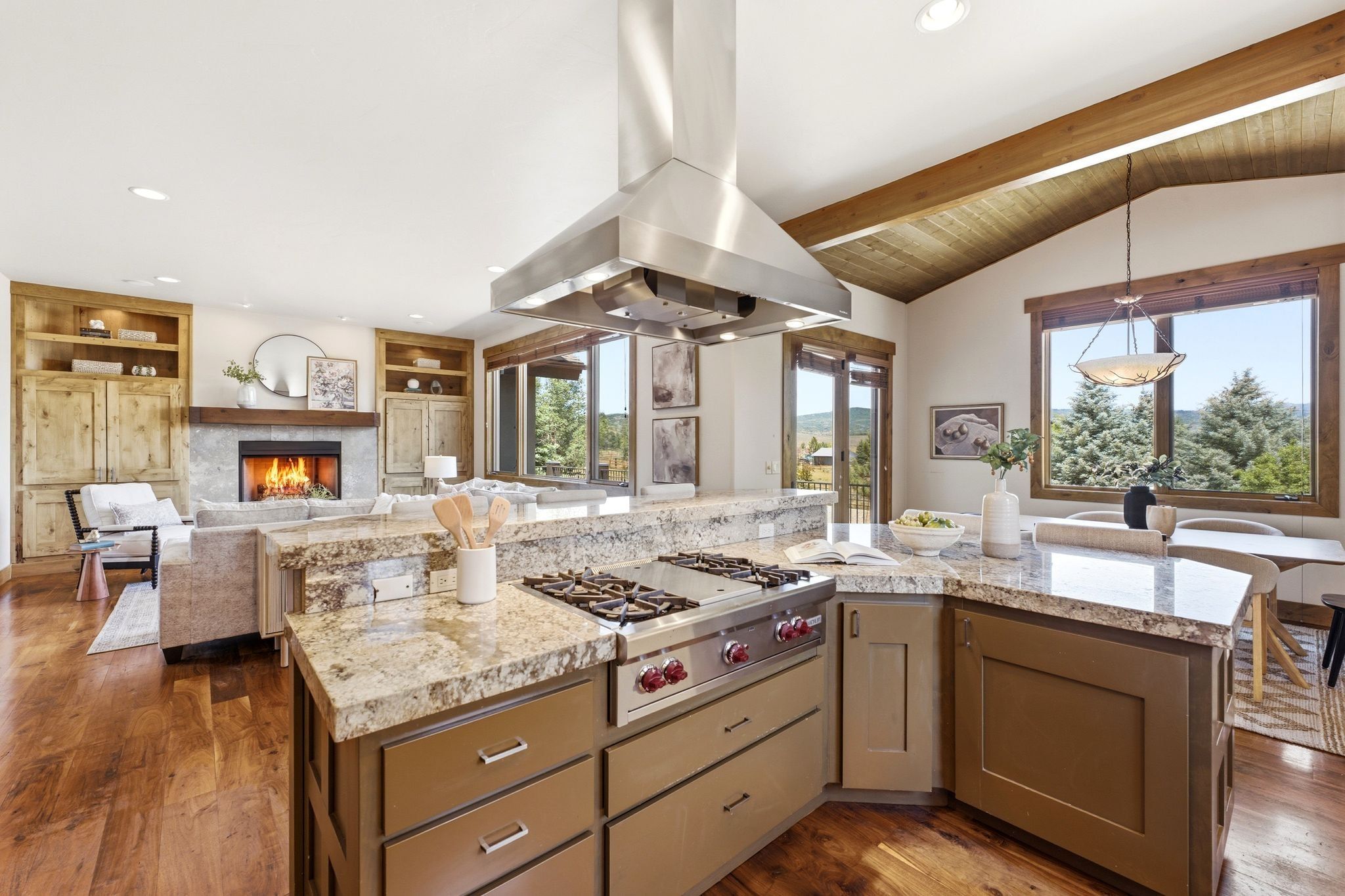 Gourmet kitchen island featuring a built-in gas range, stainless steel range hood, and granite countertops